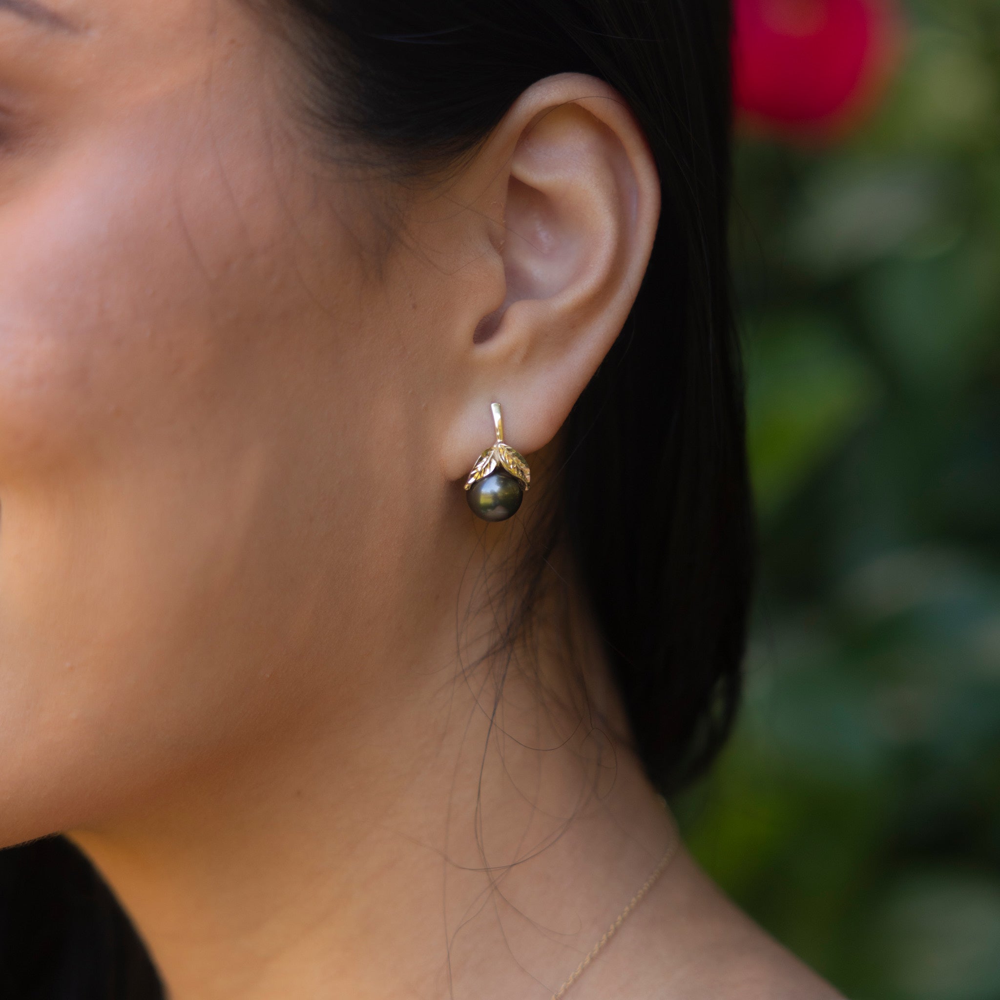 Close up of Maile Tahitian Black Pearl Earrings in Gold on Woman's Ear