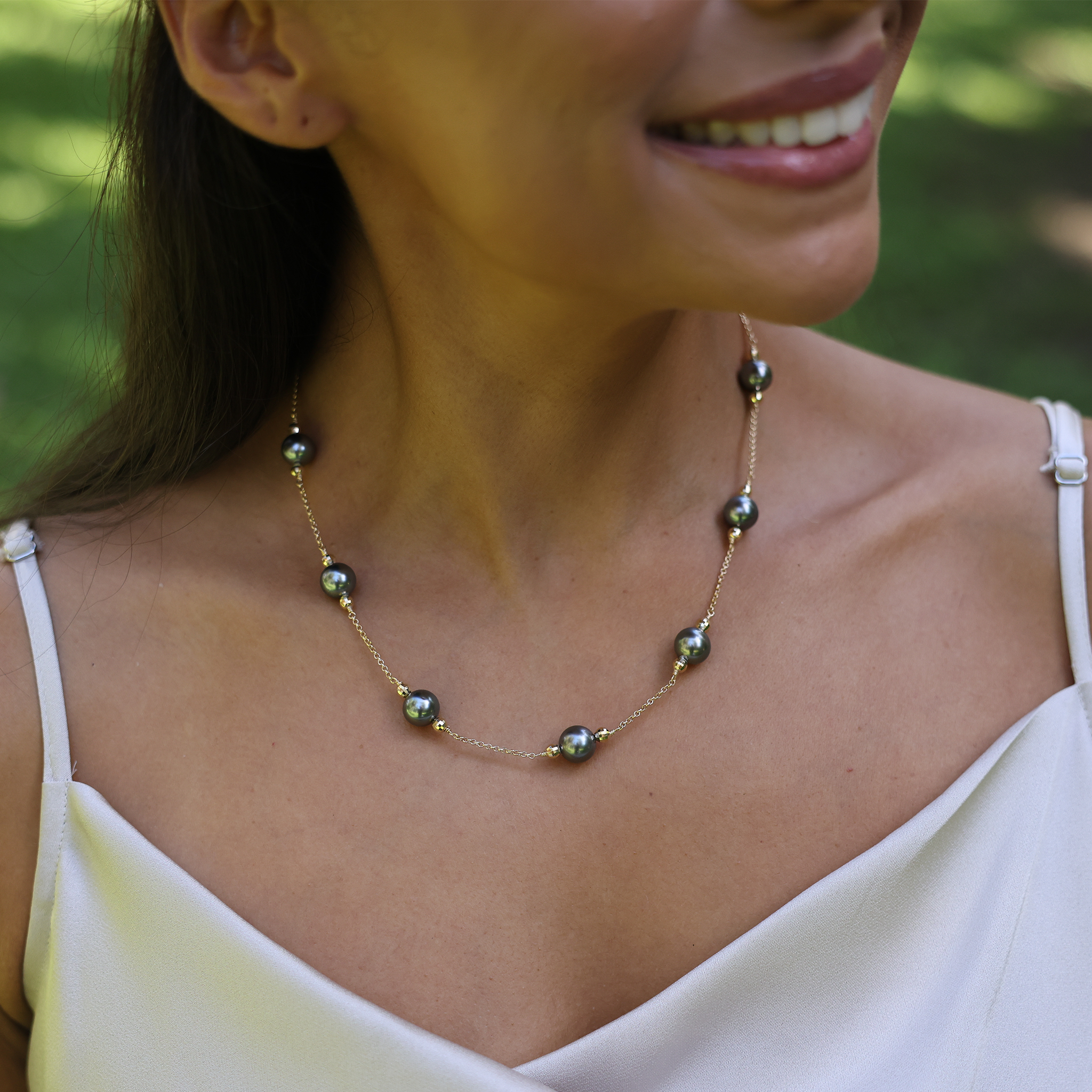 Close-up of a woman wearing a Tahitian black pearl necklace in yellow gold.