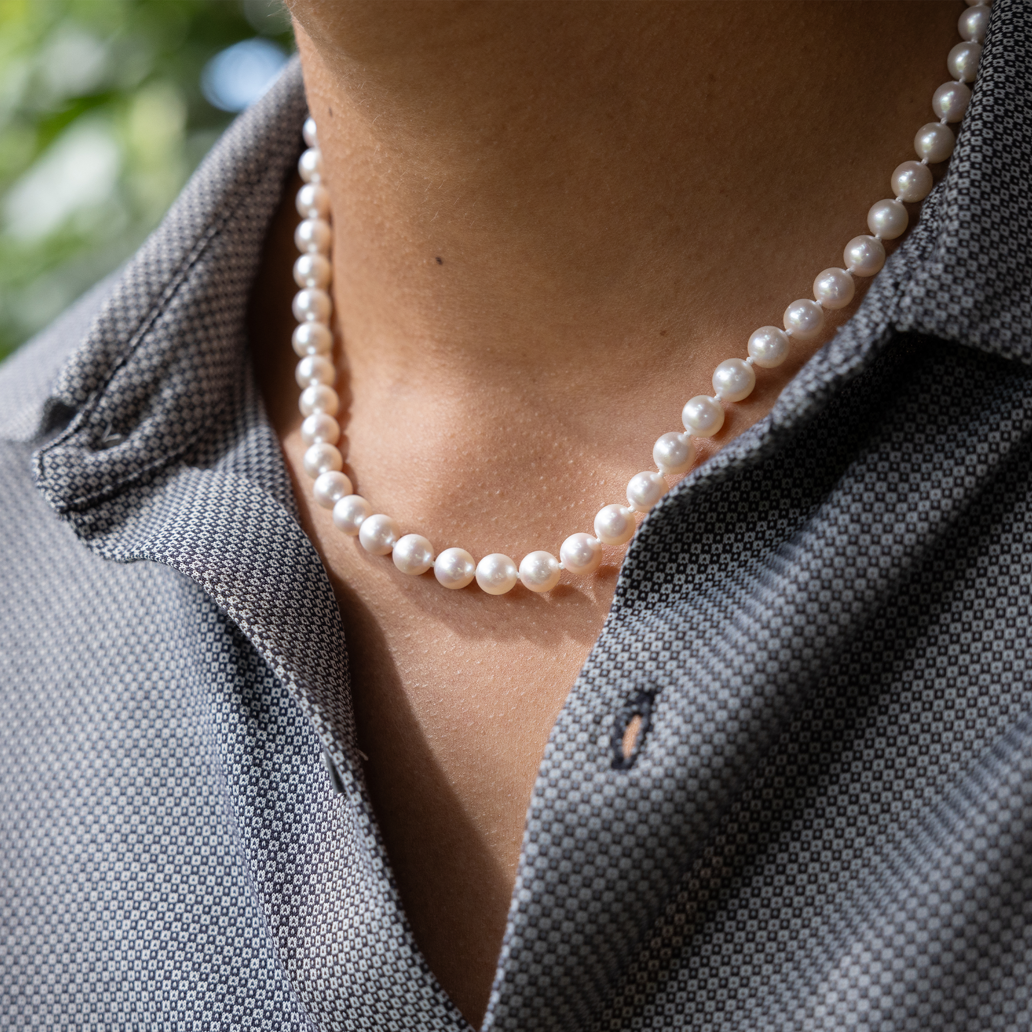 Close-up of an Akoya white pearl strand necklace worn around a neck