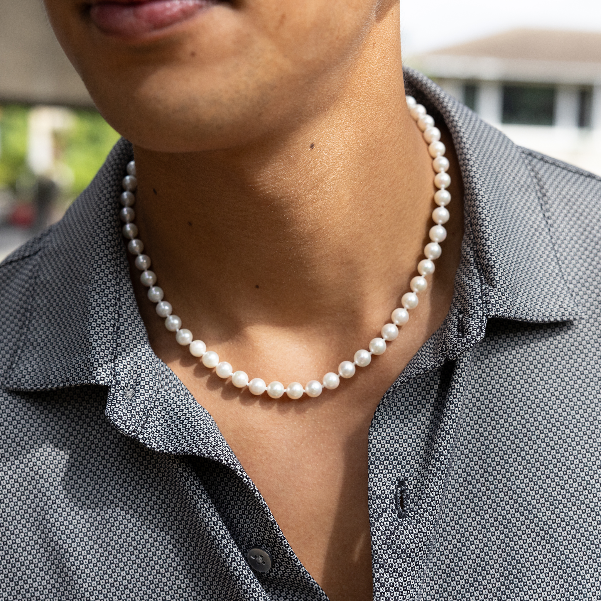 Close-up of an Akoya white pearl strand necklace worn around a man's neck