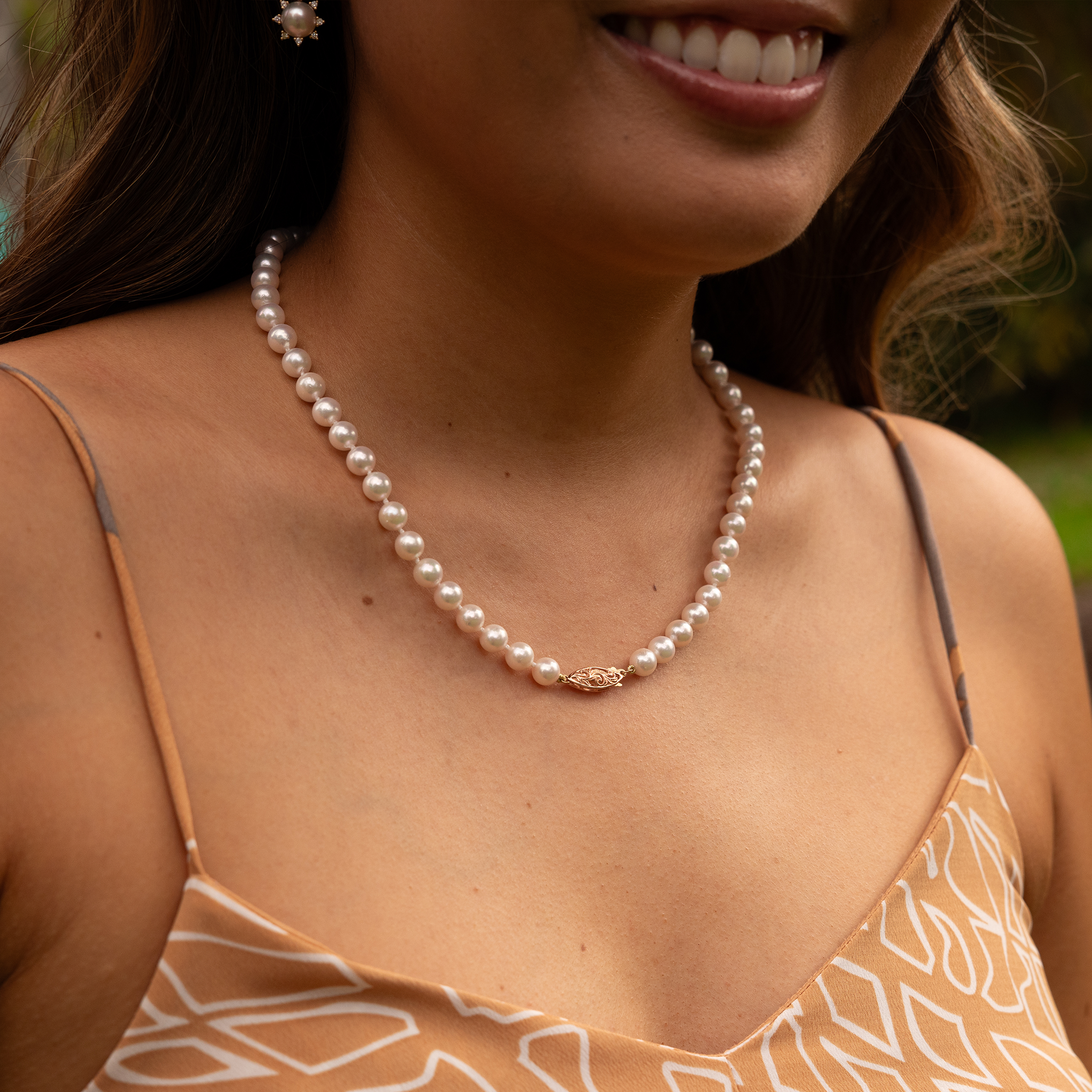 Close-up of a woman wearing an Akoya white pearl strand necklace with a 14k two-tone gold clasp