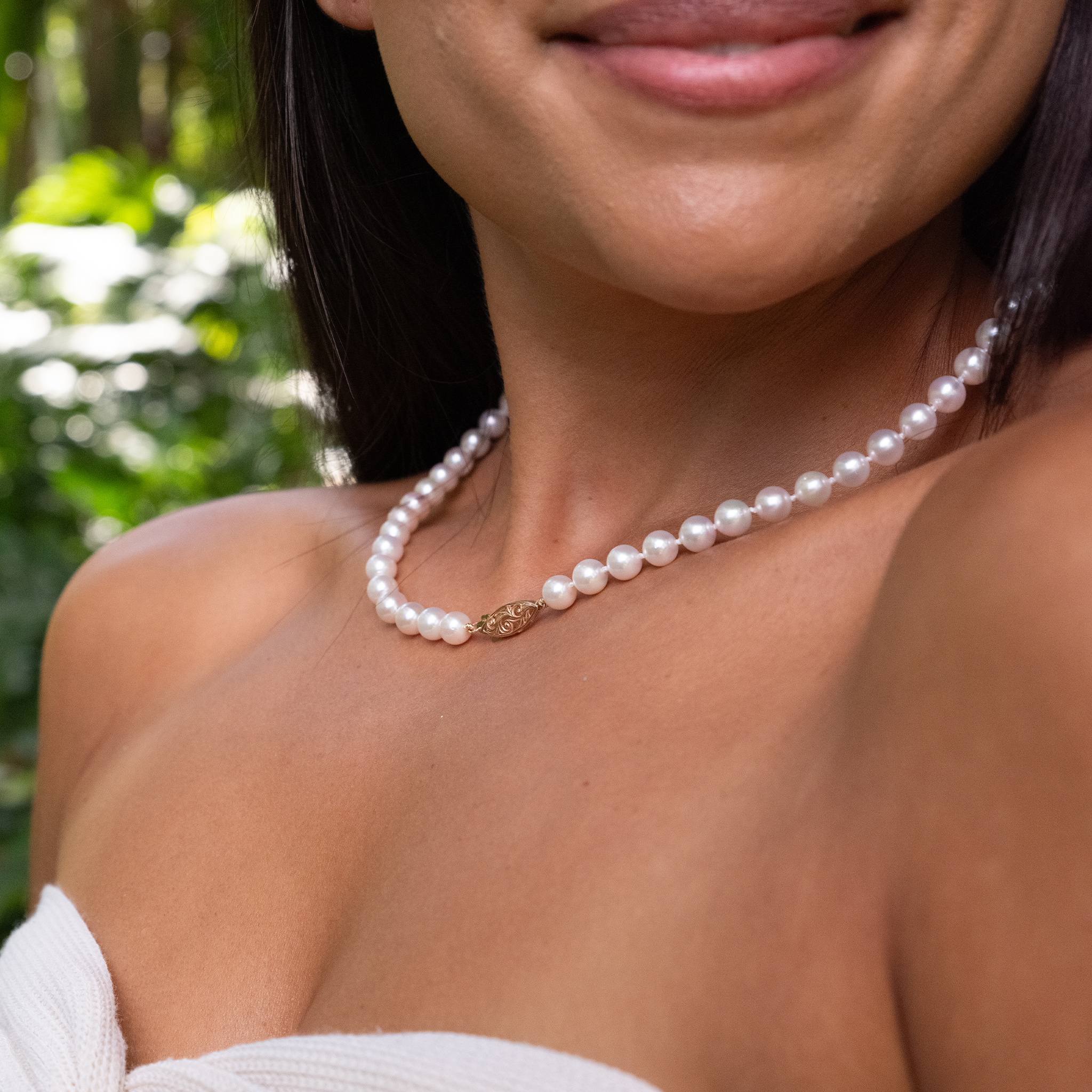 Close up of a woman wearing an Akoya white pearl strand necklace with 14k two tone gold clasp