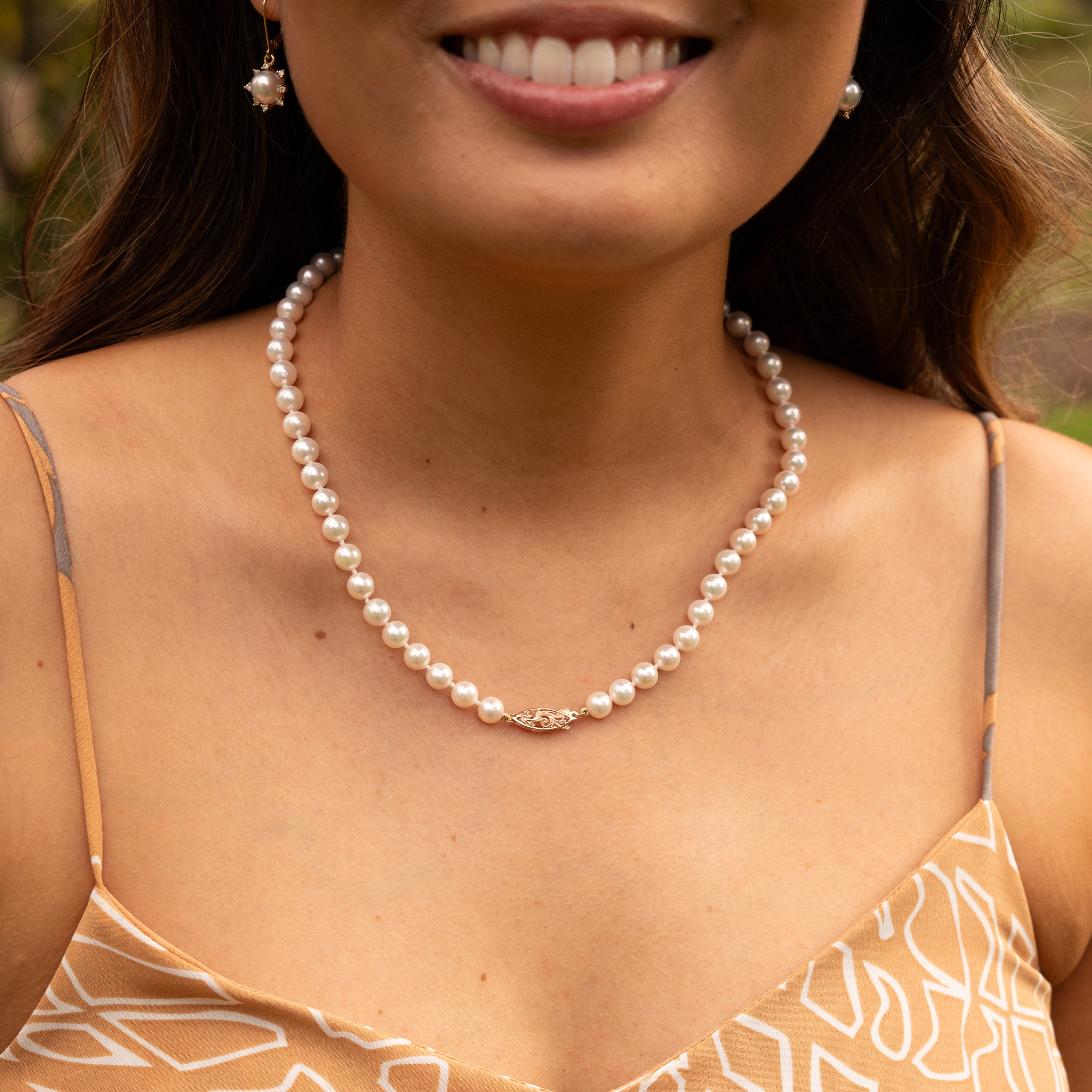 Close-up of a woman wearing an Akoya white pearl strand necklace with a 14k two tone gold clasp