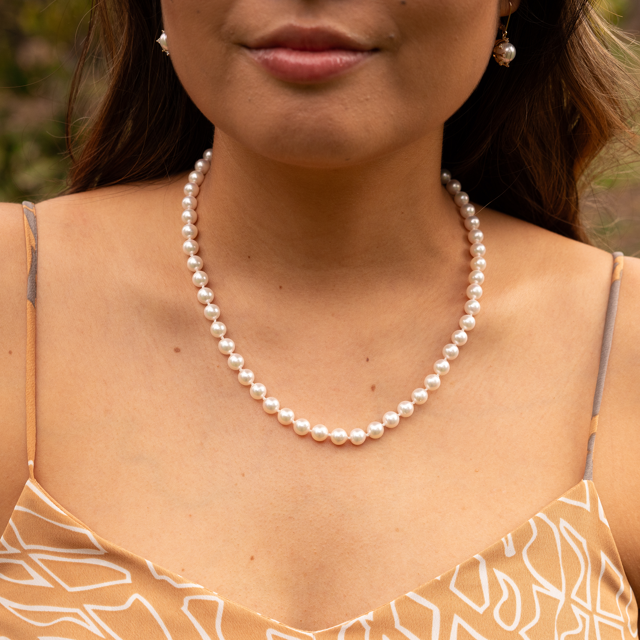 Close-up of a woman wearing an Akoya white pearl strand necklace