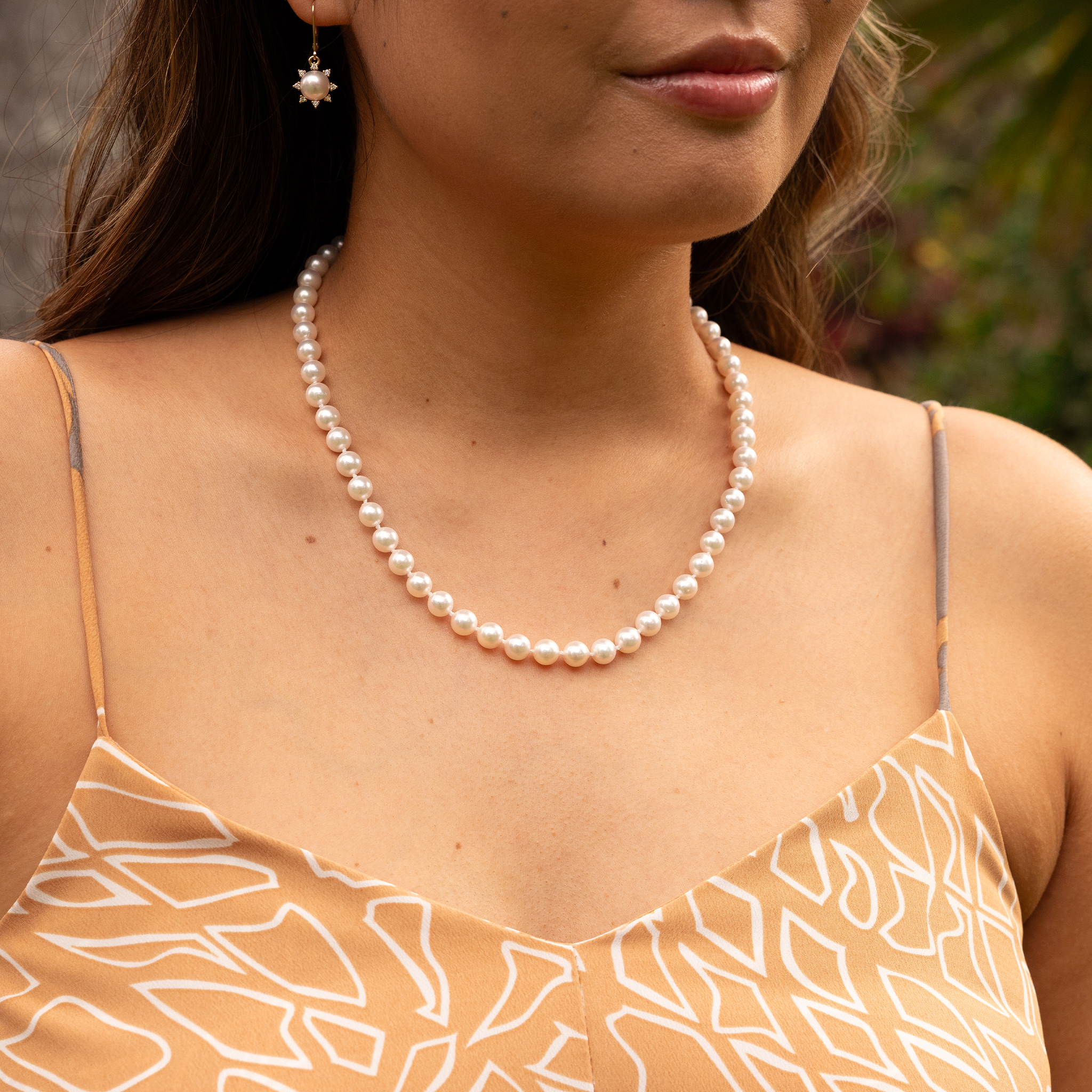 Close-up of a woman wearing an Akoya white pearl strand necklace