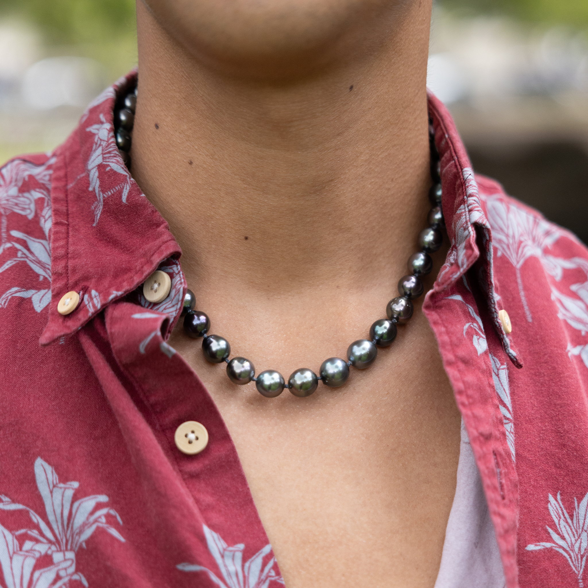 Close-up of a man in a red Aloha shirt wearing a Tahitian black pearl strand necklace