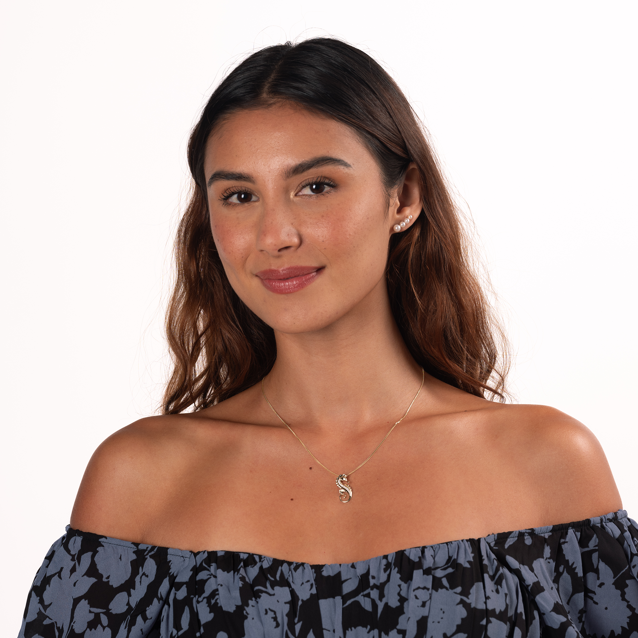 Smiling woman wearing a four-pearl gradient earring with Akoya and freshwater white pearls, with a 14k yellow gold seahorse pendant on a 14k yellow gold chain against a white background.