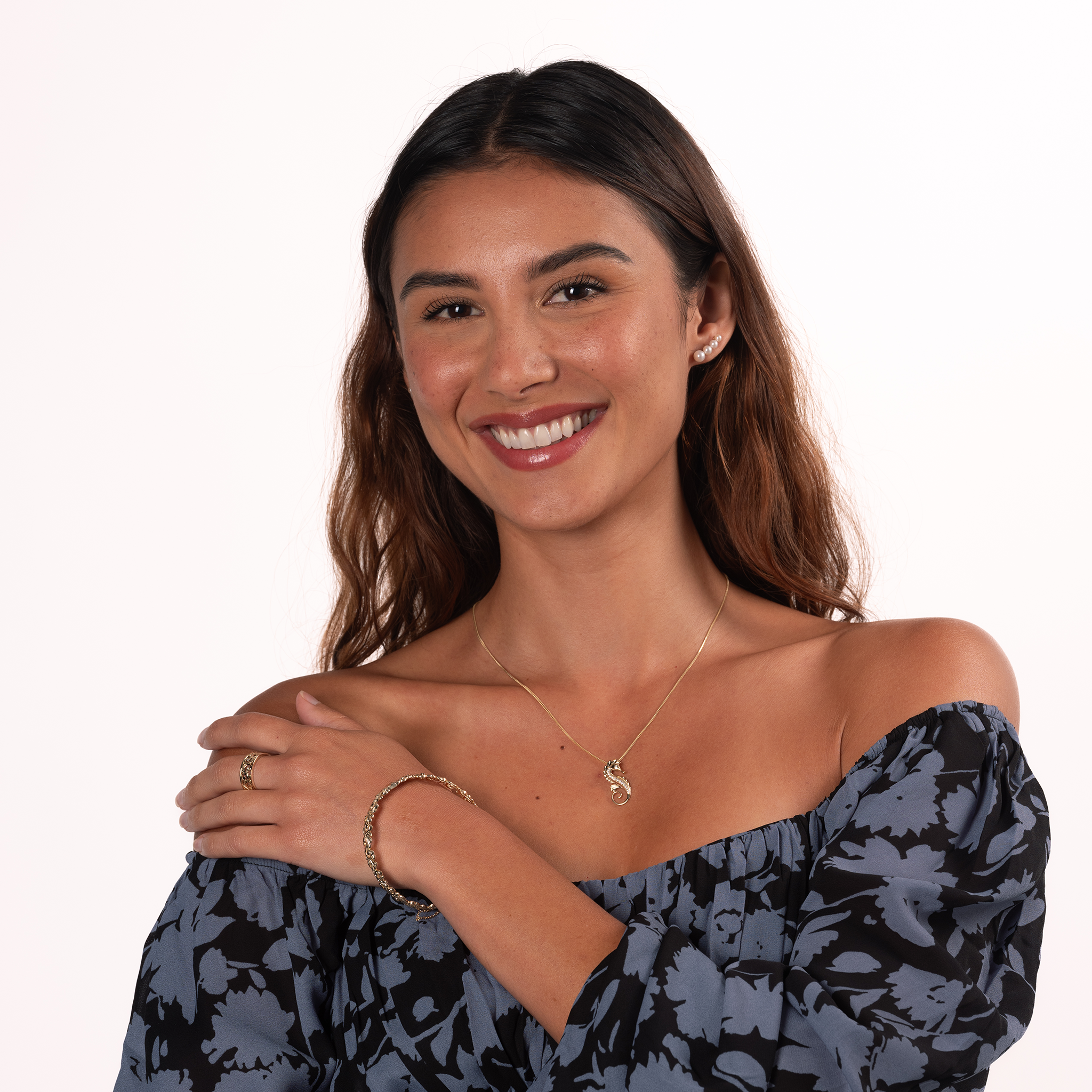 Smiling woman wearing a four-pearl gradient earring with Akoya and freshwater white pearls, with a 14k yellow gold seahorse pendant on a 14k yellow gold chain against a white background.