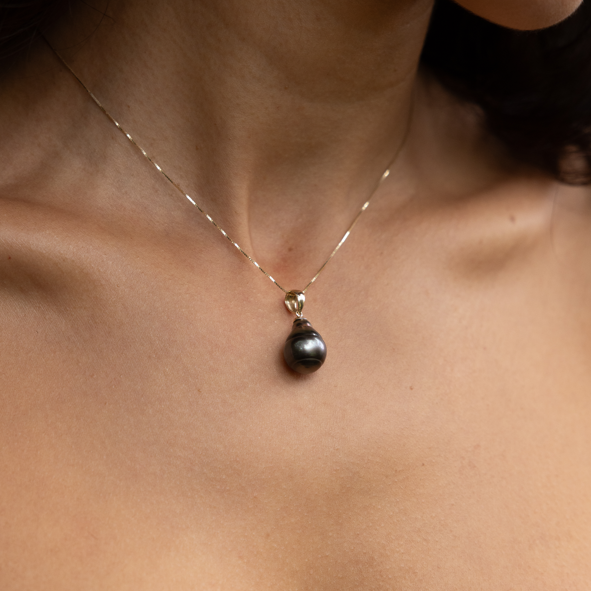 Close up of a 8-12mm Tahitian Black Pearl Pendant in Gold on a woman's chest