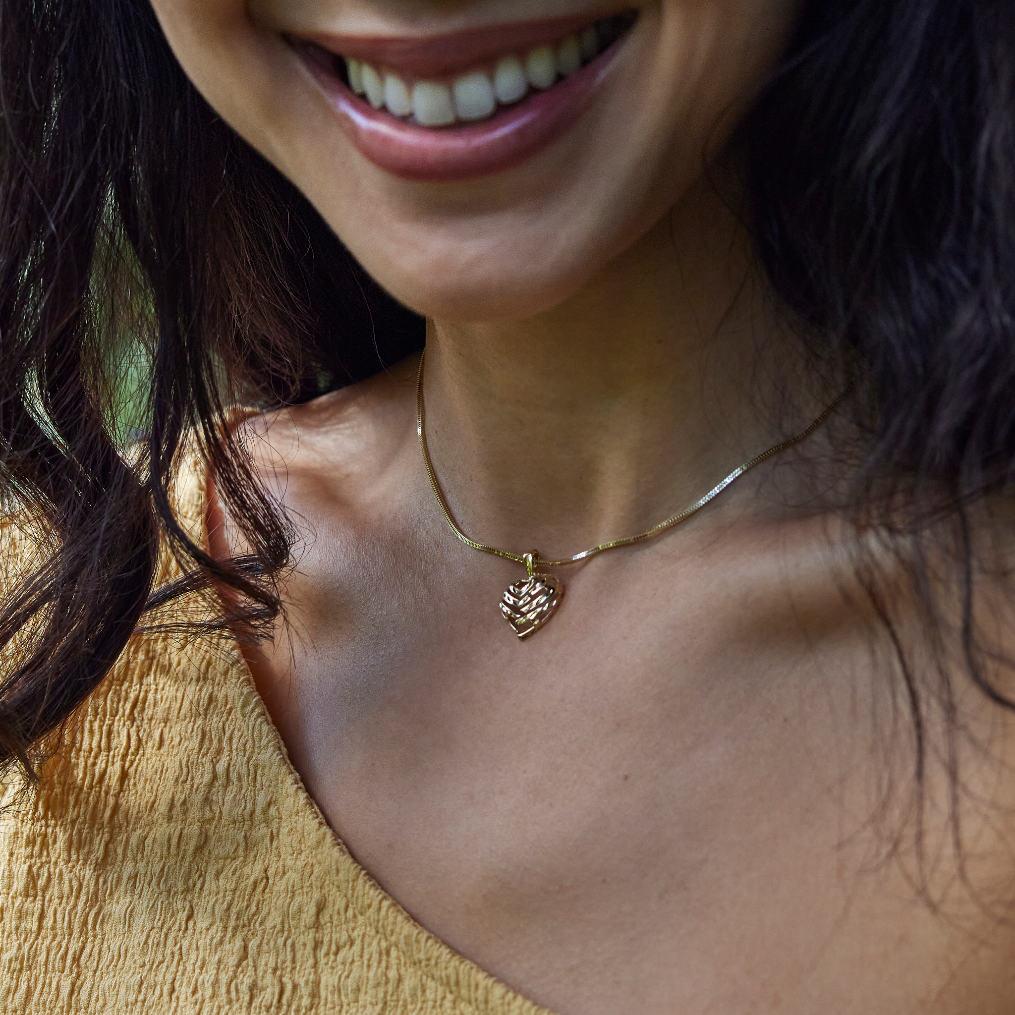 Close up of woman wearing yellow gold Aloha Heart Pendant with cut-out design on chain