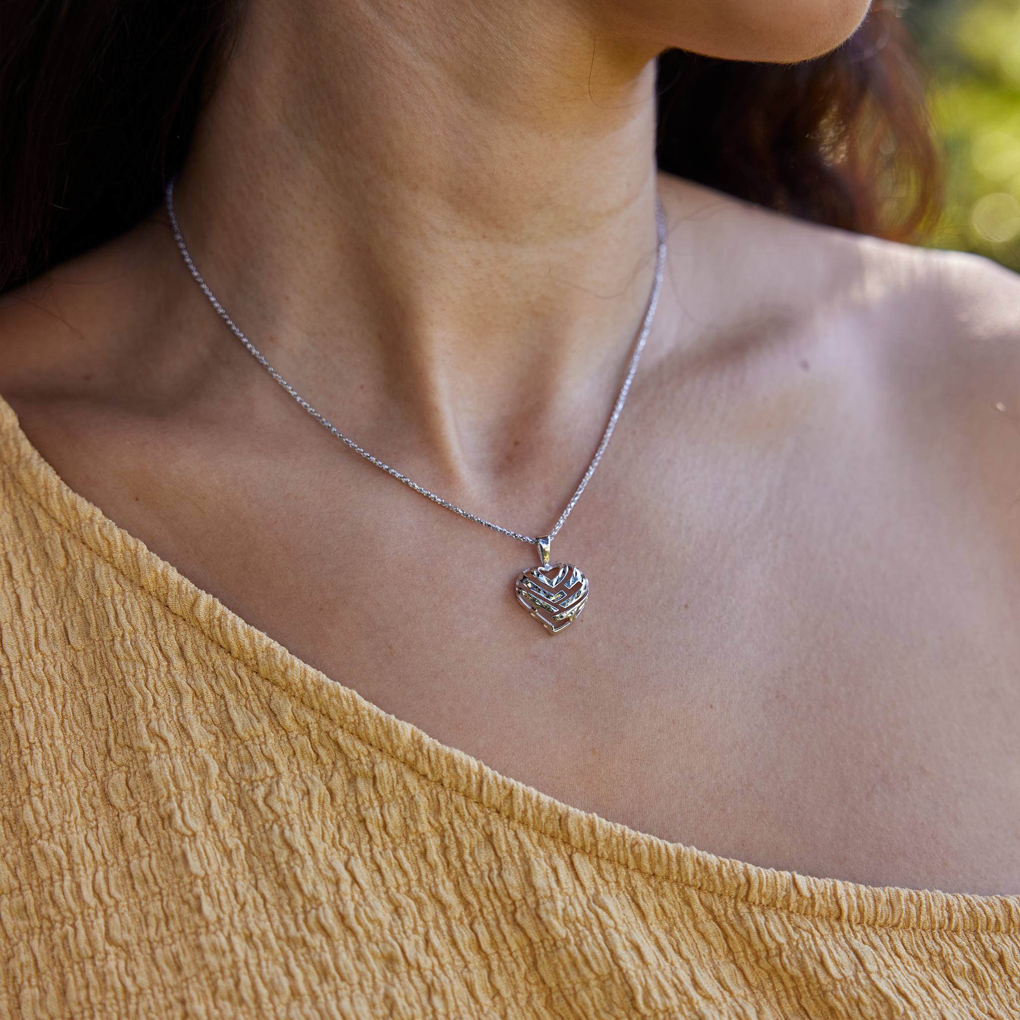 Close-up of a person wearing an Aloha Heart Pendant with cut-out design spelling "Aloha" in 14k White Gold on chain