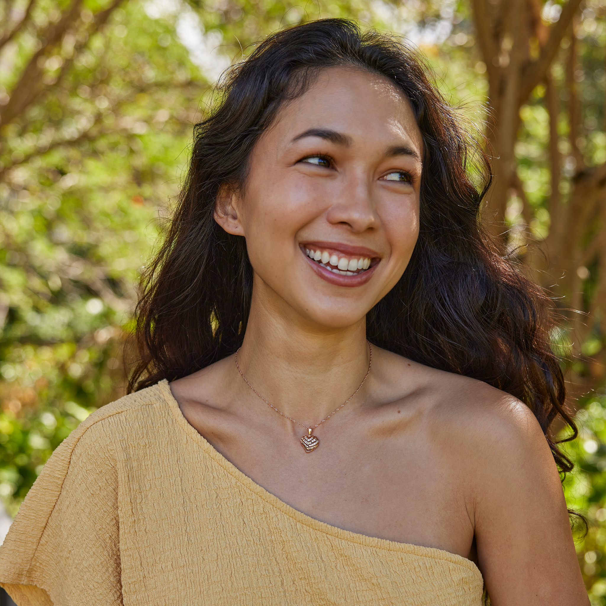Close-up of a woman wearing an Aloha Heart Pendant with cut-out design spelling "Aloha" in 14k Rose Gold on chain