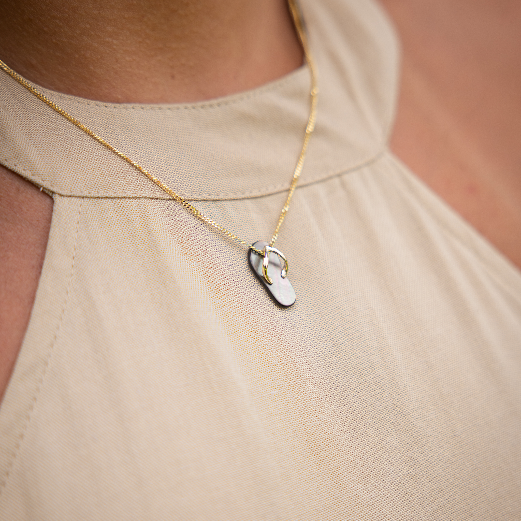 Macro close-up of Black Mother of Pearl Slipper Pendant with Gold Straps hanging on Yellow Gold Chain