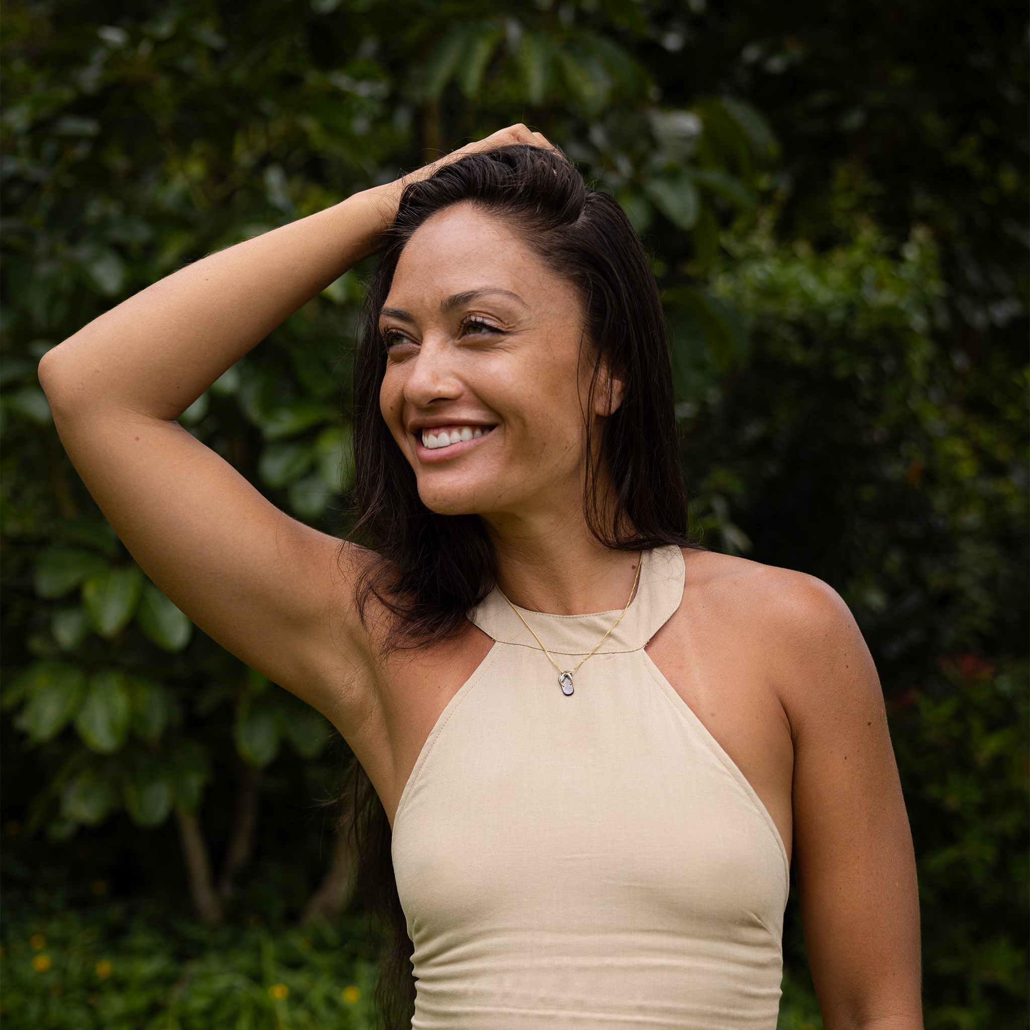 Smiling woman in front of greenery wearing a Black Mother of Pearl Slipper Pendant on Gold Chain