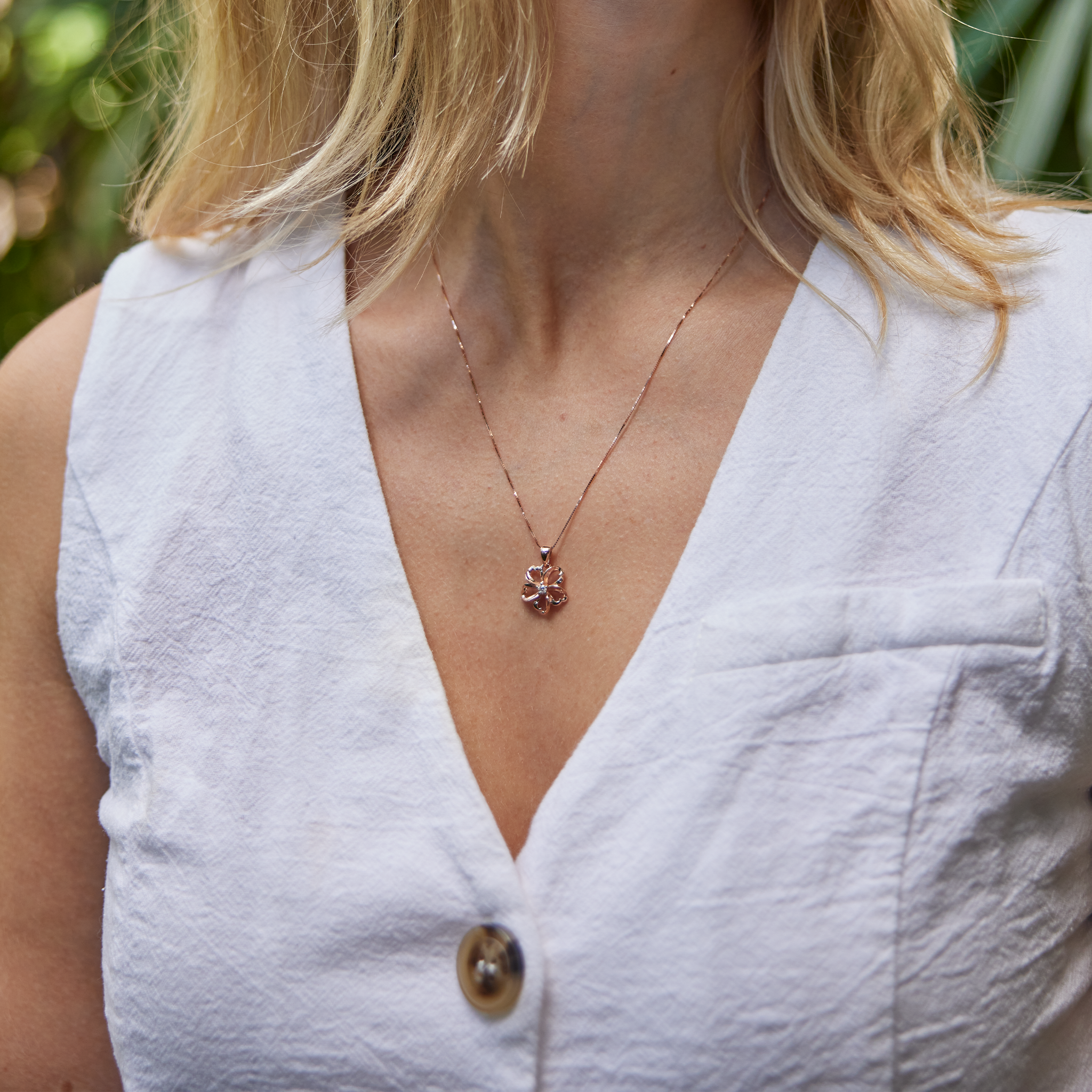 Close up of woman wearing a cut-out design Plumeria Necklace with Diamond Center in 14k Rose Gold