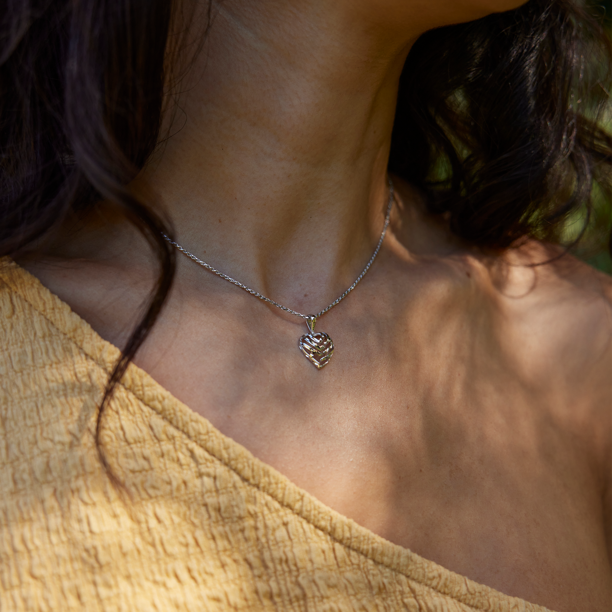 Neckline of woman wearing white gold Aloha Heart Pendant on chain