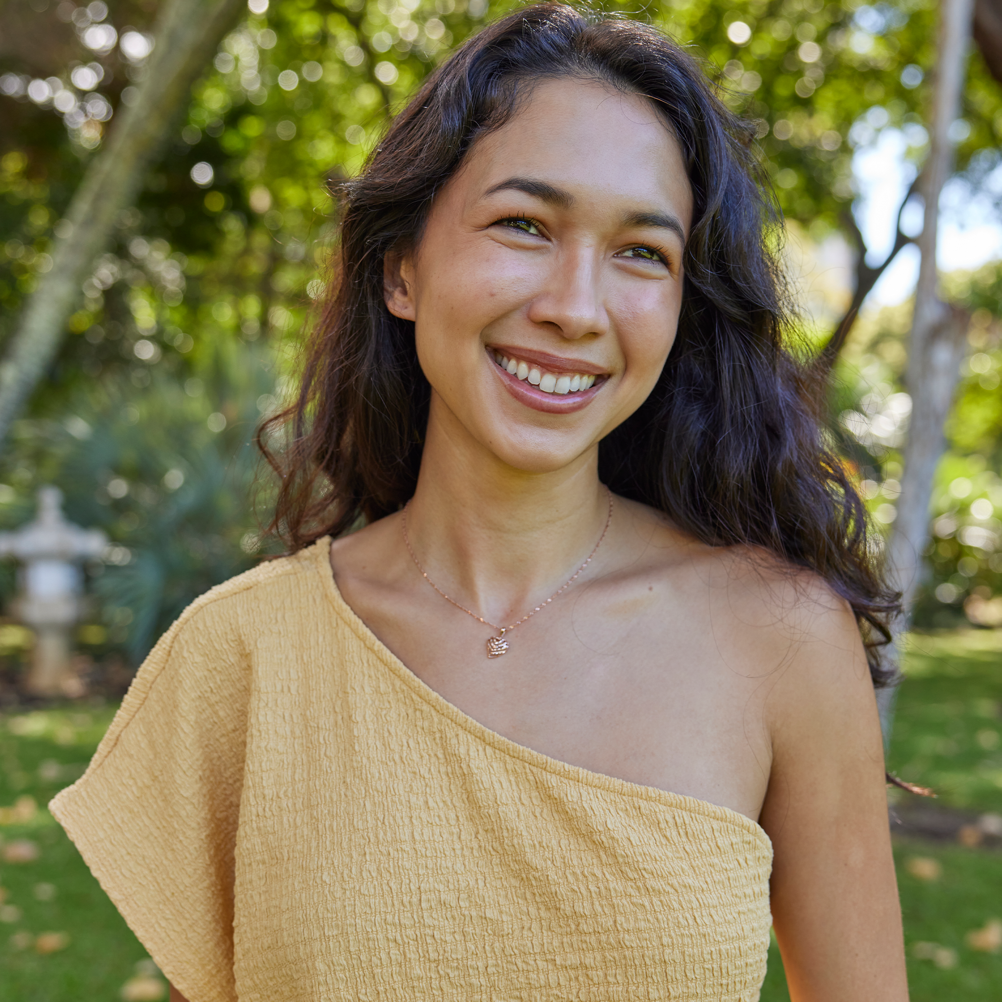 Smiling woman in garden wearing Rose Gold Aloha Heart Pendant with cut-out design on Chain