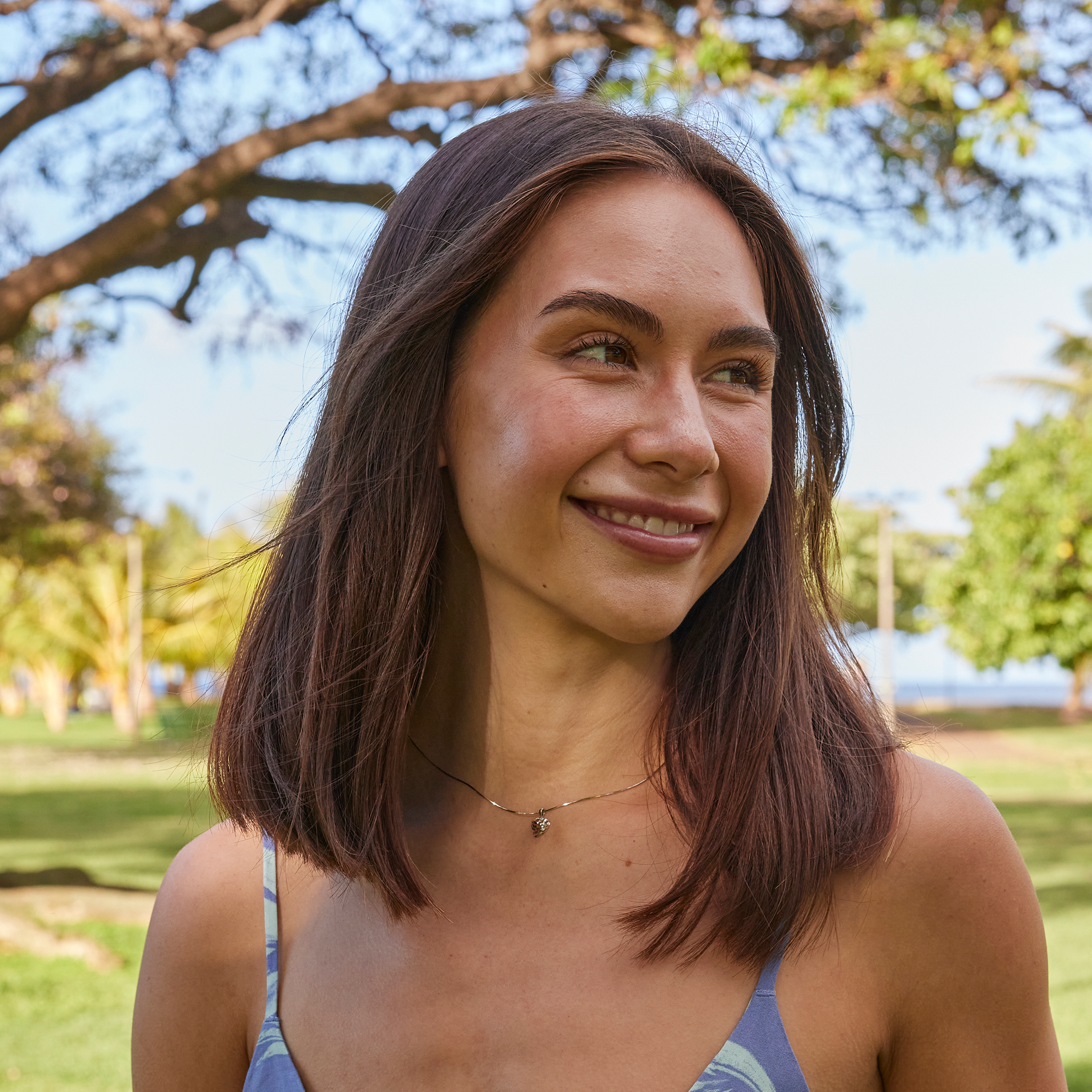 Smiling woman at a beach park wearing a white gold Aloha Heart pendant on chain