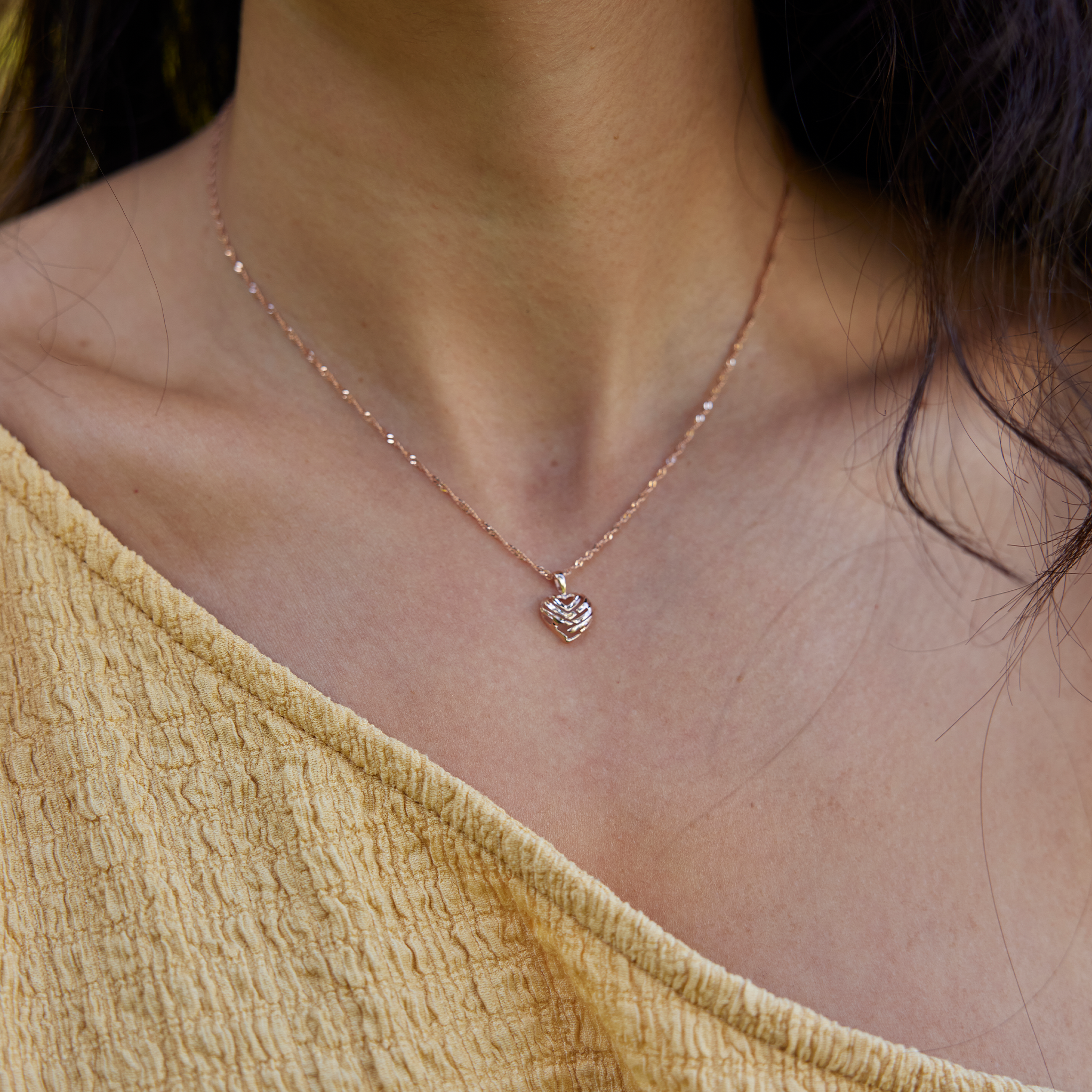 Neckline of woman wearing rose gold cut-out Aloha Heart Pendant on singapore chain