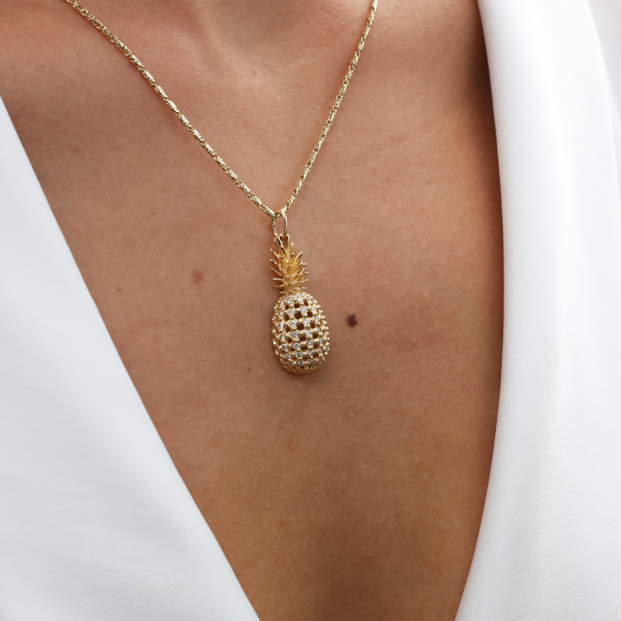 Close up of 1.4mm Raso Chain in Goldand a pineapple pendant on a woman's chest