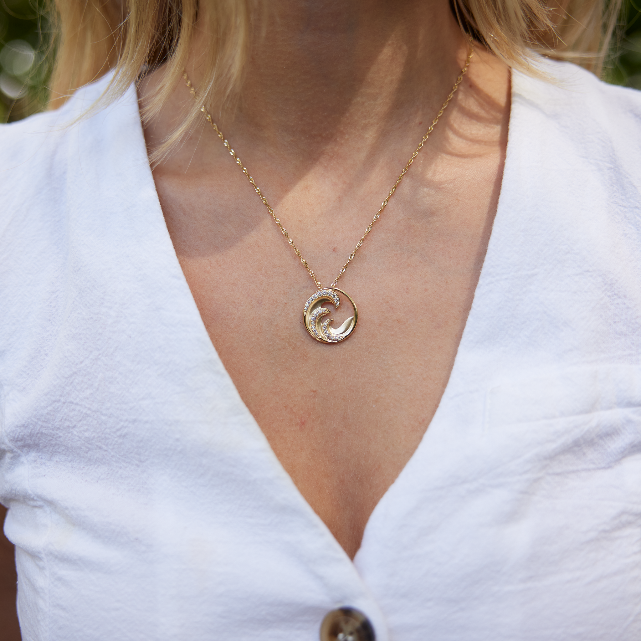 Close up of Nalu wave Pendant in Gold with Diamonds on neckline