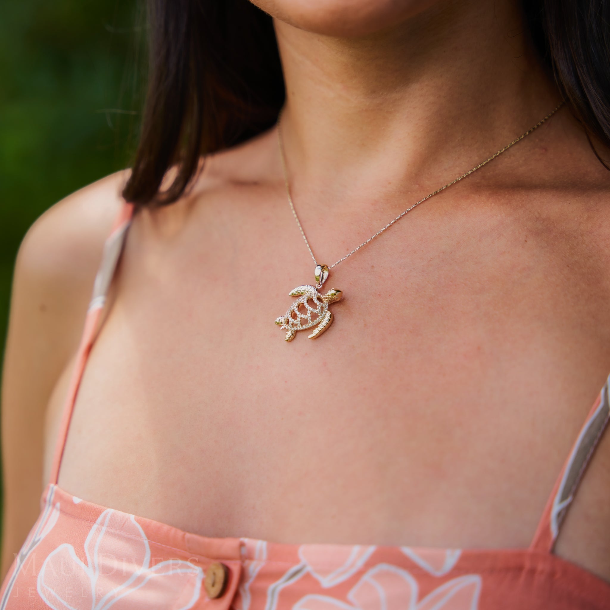 Woman's chest with a 0.9mm Raso Chain in 14k Yellow Gold and turtle pendant outdoors