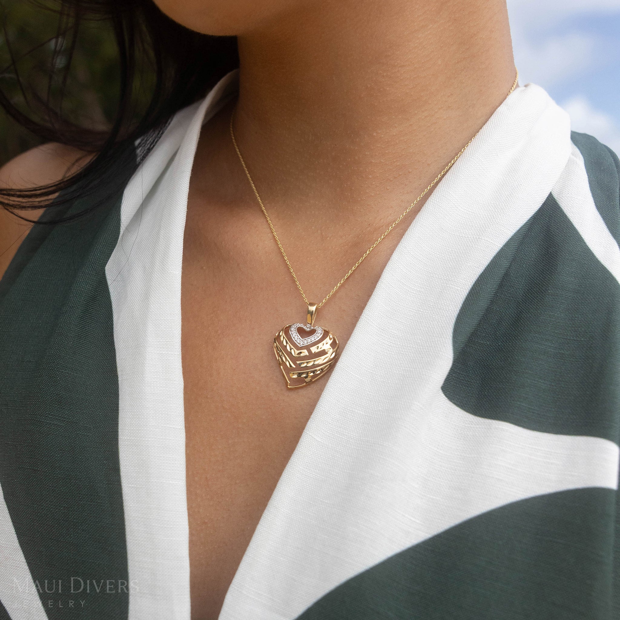 Two-tone gold necklace with a heart-shaped pendant and diamonds worn by a woman