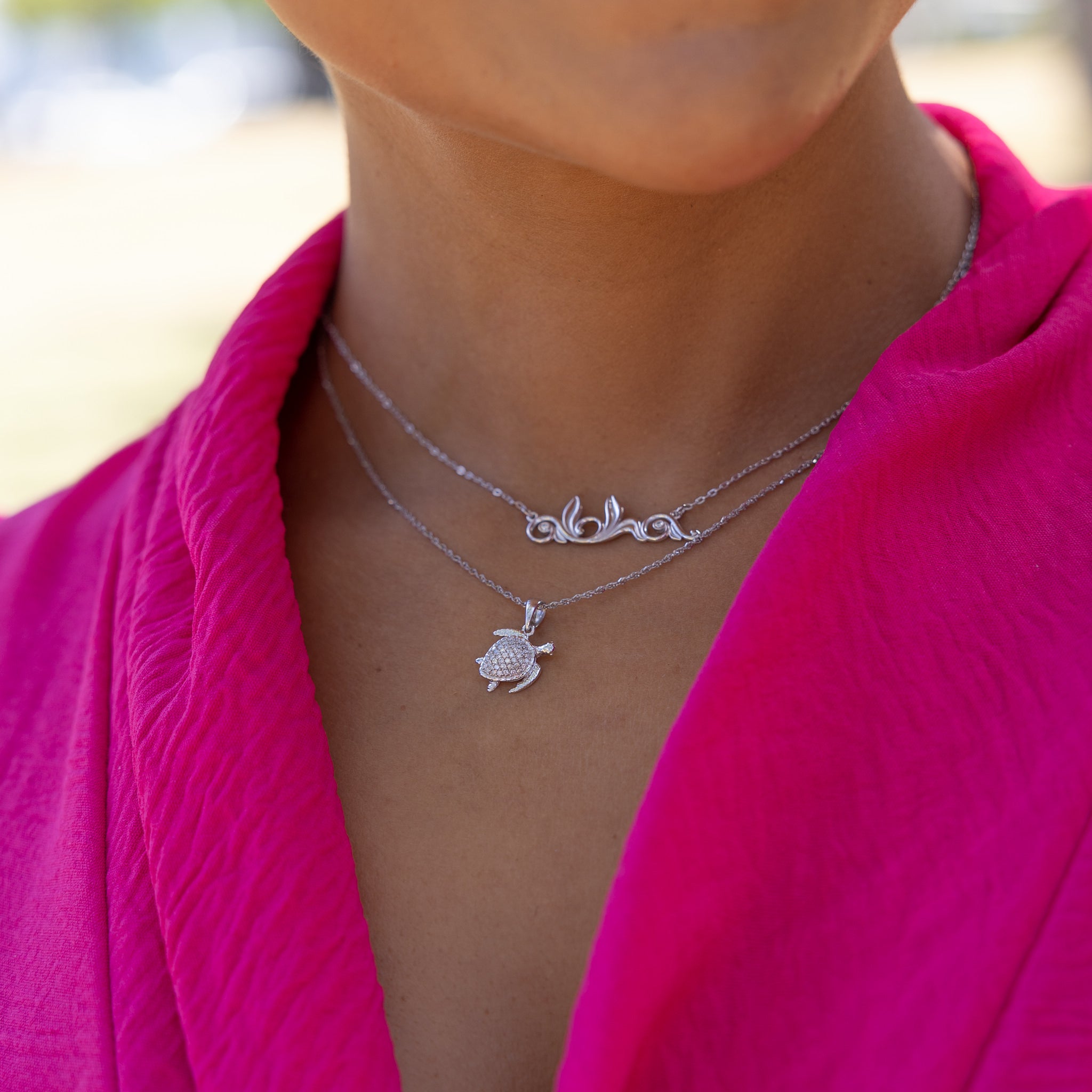 Woman wearing 0.8mm Baby Rope Chain in White Gold with turtle and aloha pendants outdoors