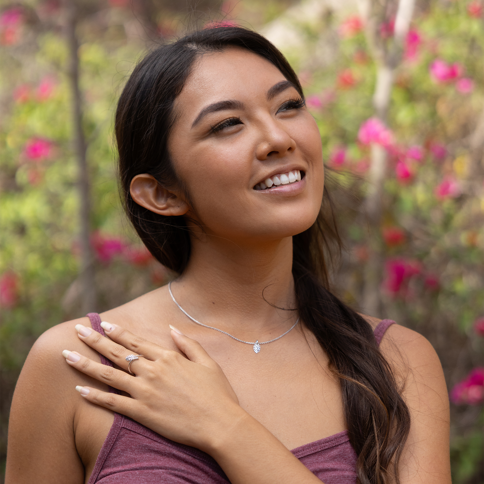 Woman in a floral garden wearing Monstera ring and pendant in white gold on cable chain