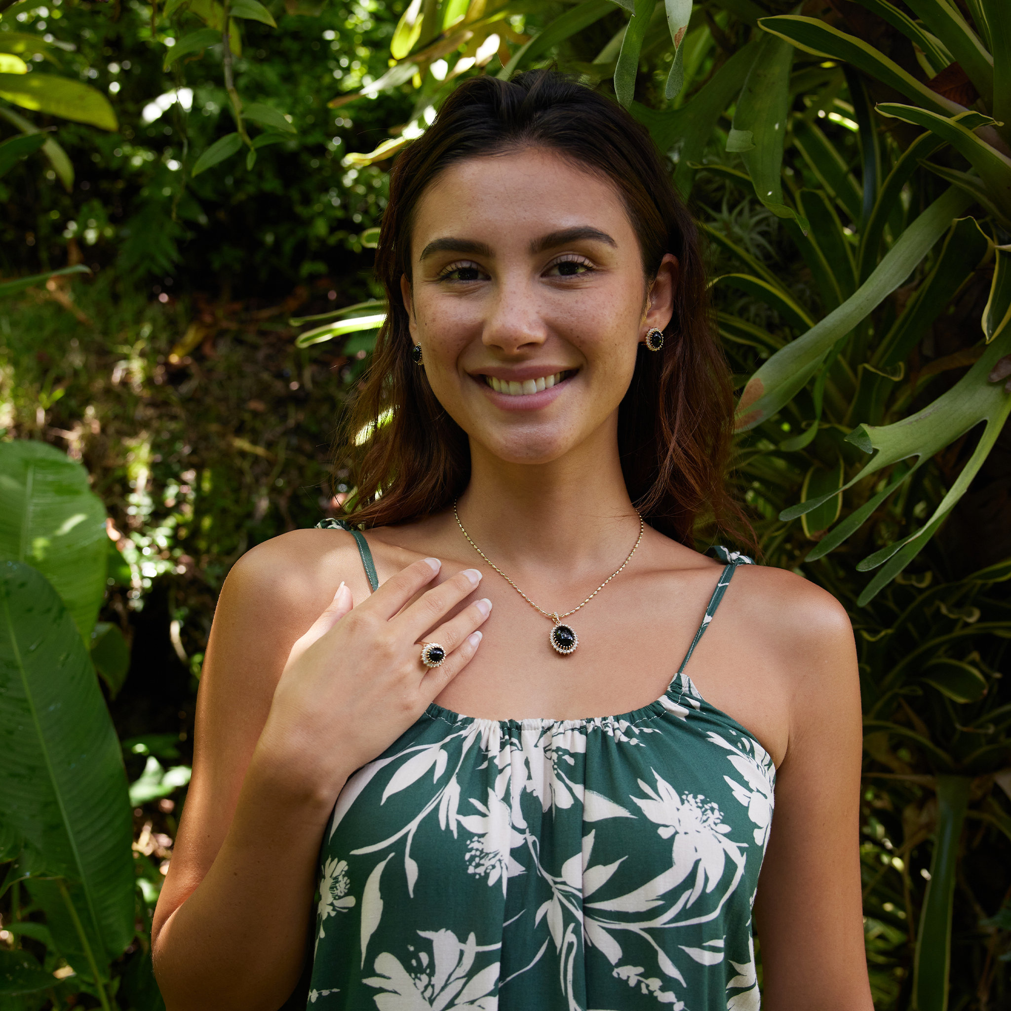 Woman in a tropical garden wearing Princess Ka‘iulani Black Coral Pendant, earrings and ring in Gold with Diamonds