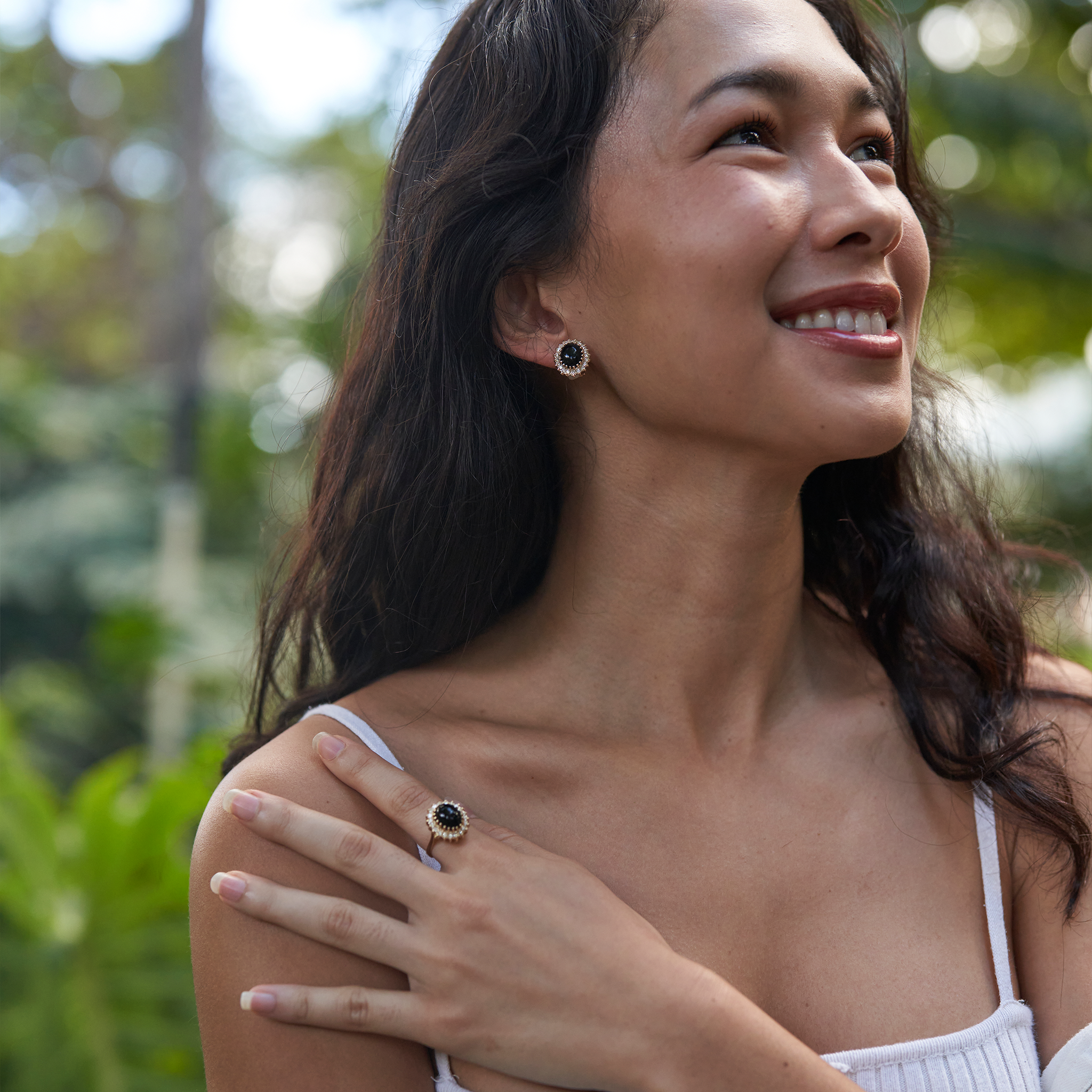 Woman in garden wearing Princess Ka‘iulani Black Coral Ring and earrings in Gold with Diamonds