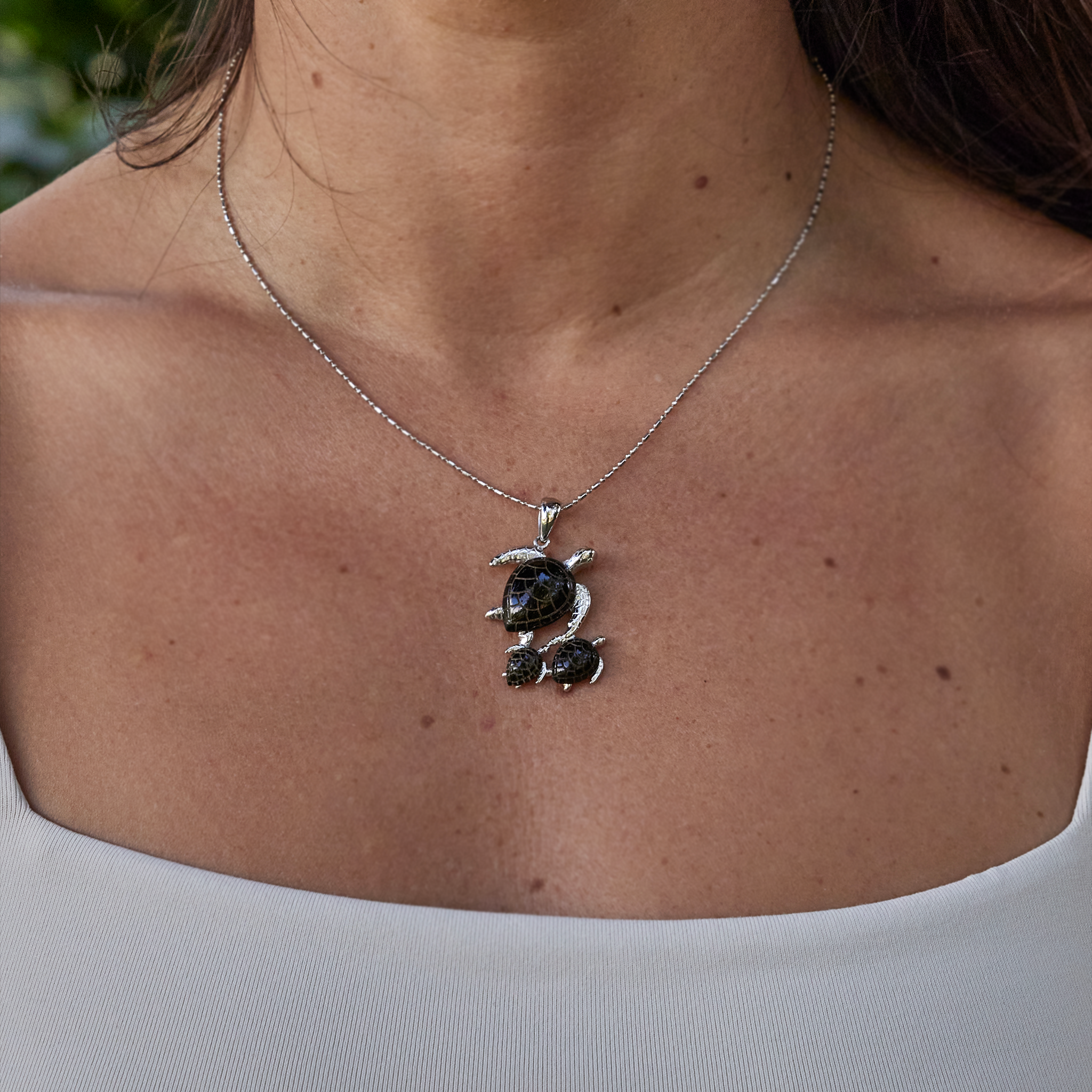 Close up of woman wearing Honu Mom & two babies Black Coral Pendant in white gold