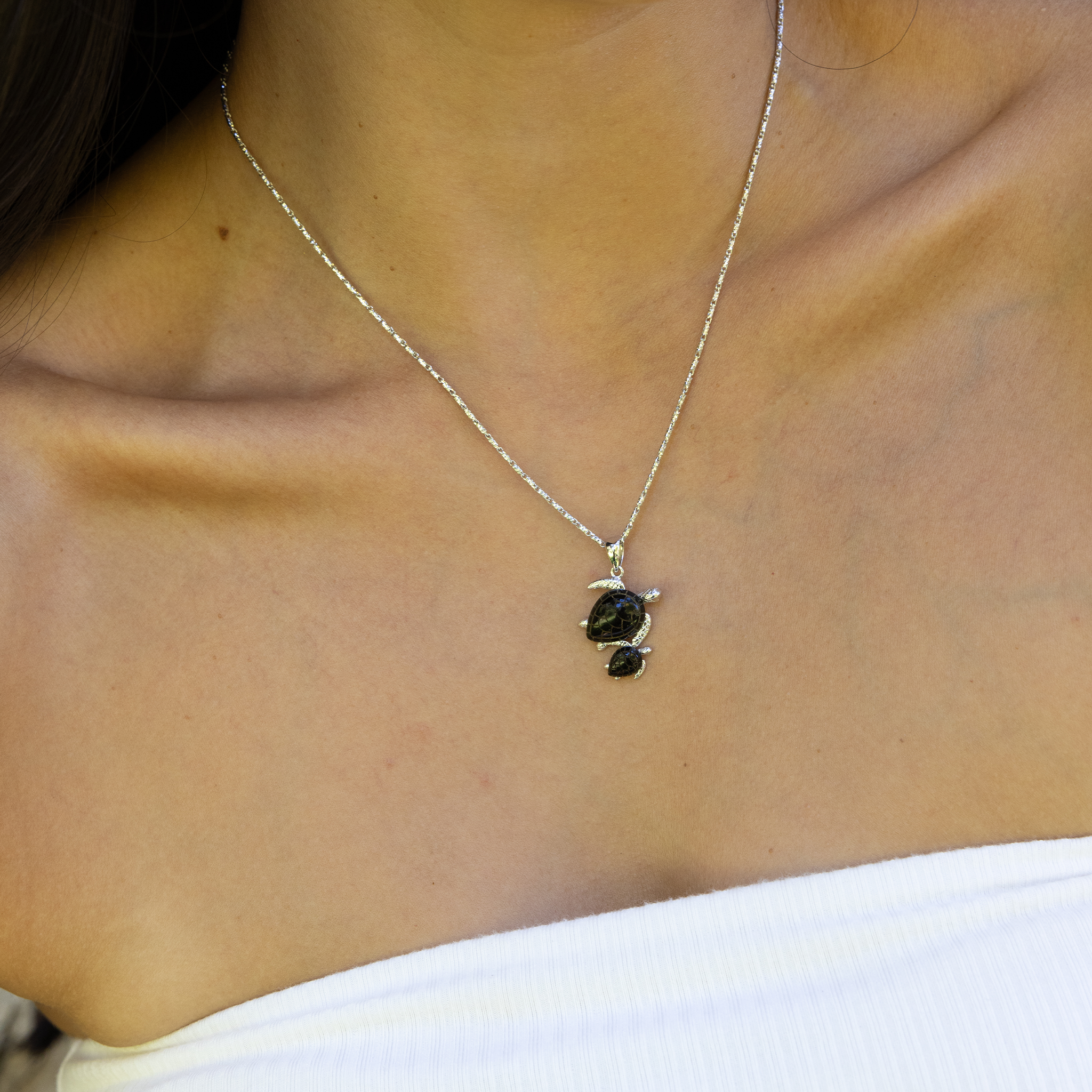 Close up of a woman wearing a Honu Mom & Baby Black Coral Pendant in White Gold