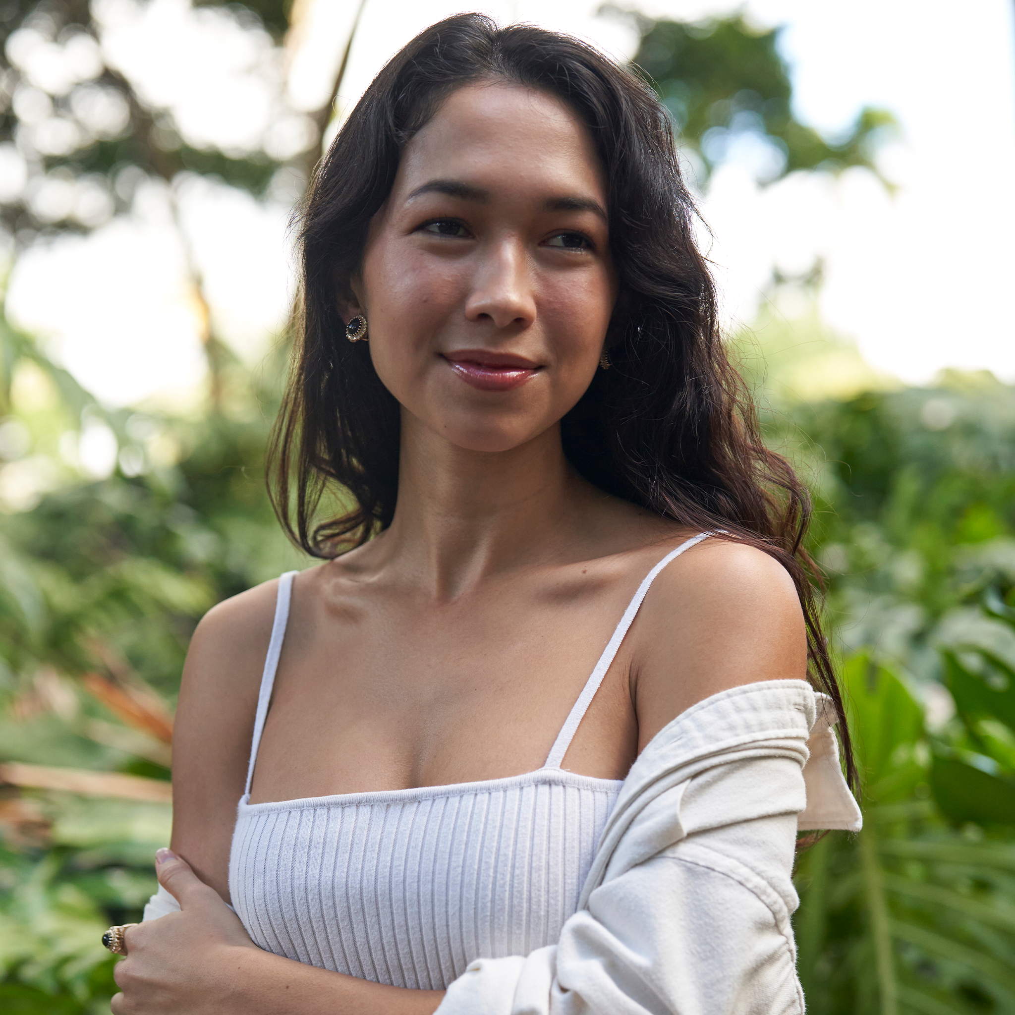 Woman in a tropical garden wearing a Princess Ka‘iulani Black Coral Earrings in Gold with Diamonds