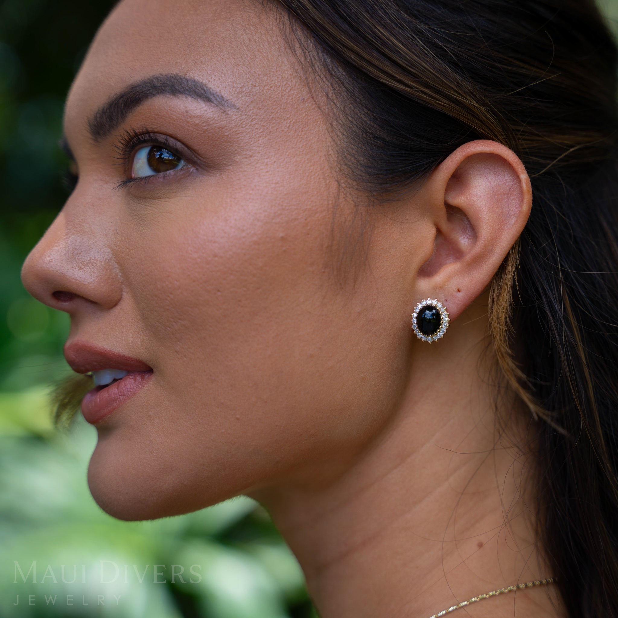 Close-up of a woman wearing a Princess Ka‘iulani Black Coral Earrings in Gold with Diamonds in garden