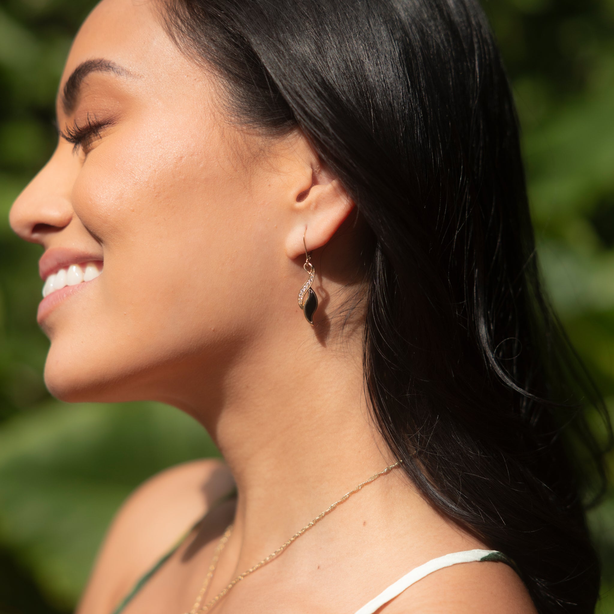 Woman smiling in sunshine wearing Paradise Black Coral Earrings in Gold with Diamonds