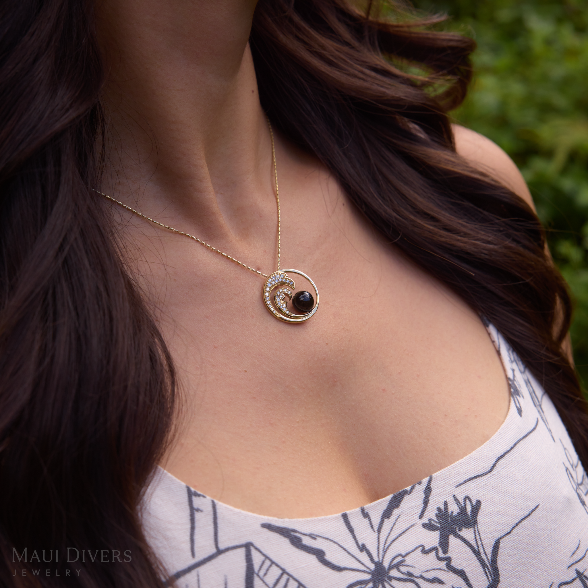 Close up of the Nalu Black Coral Pendant in Gold with Diamonds worn by a woman