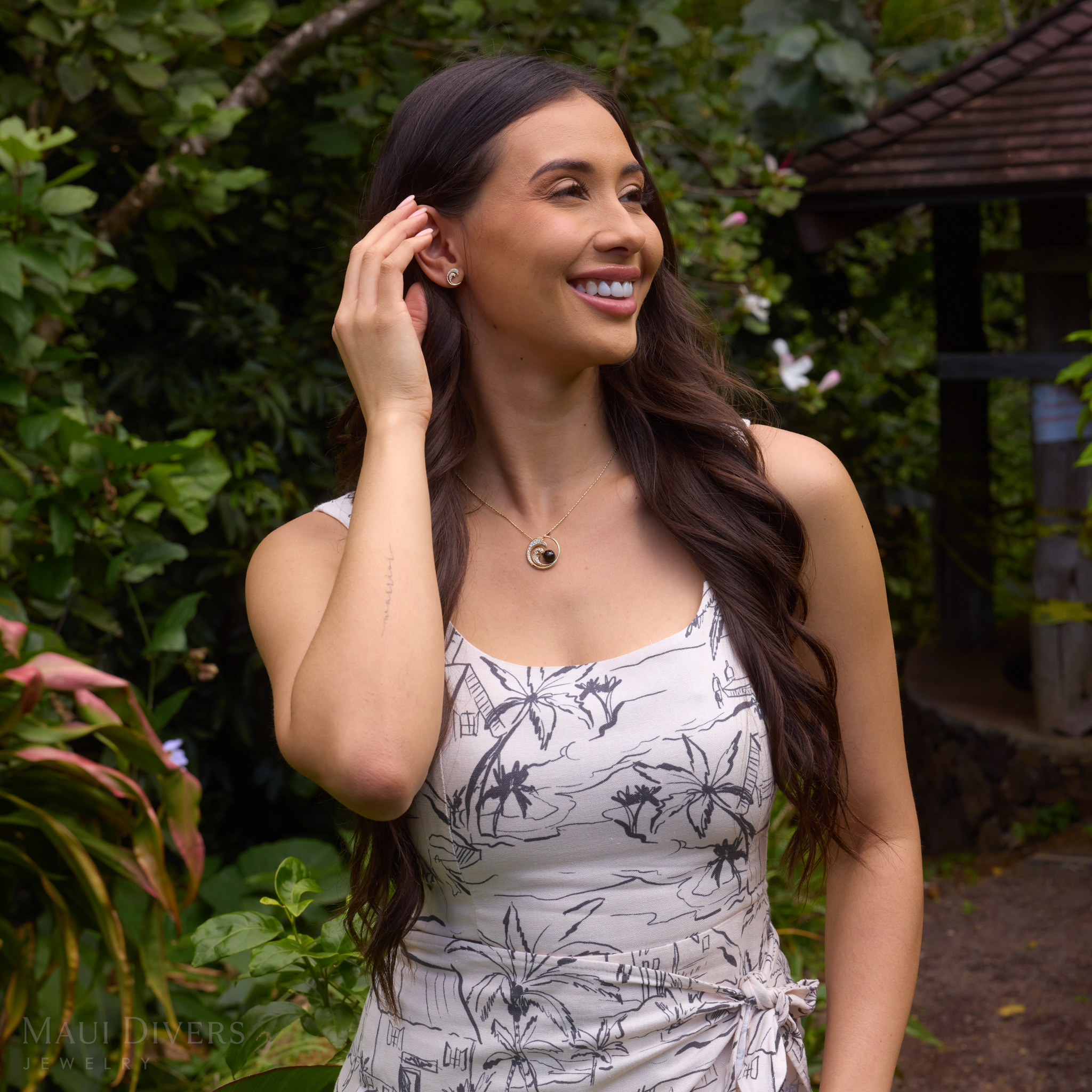 Woman in a garden wearing a Nalu Black Coral Pendant in Gold with Diamonds