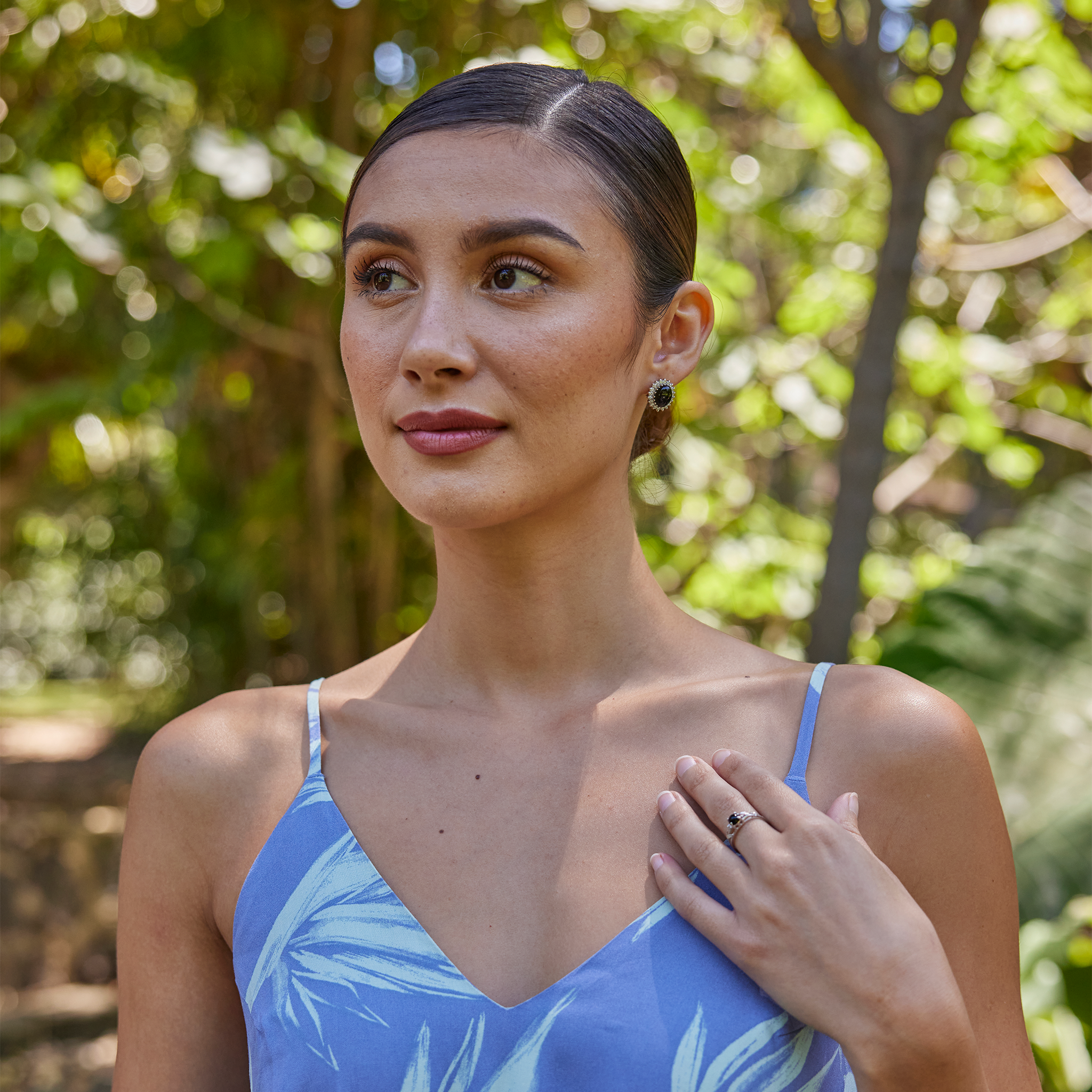 Woman in garden wearing Princess Ka‘iulani Black Coral Earrings in White Gold with Diamonds