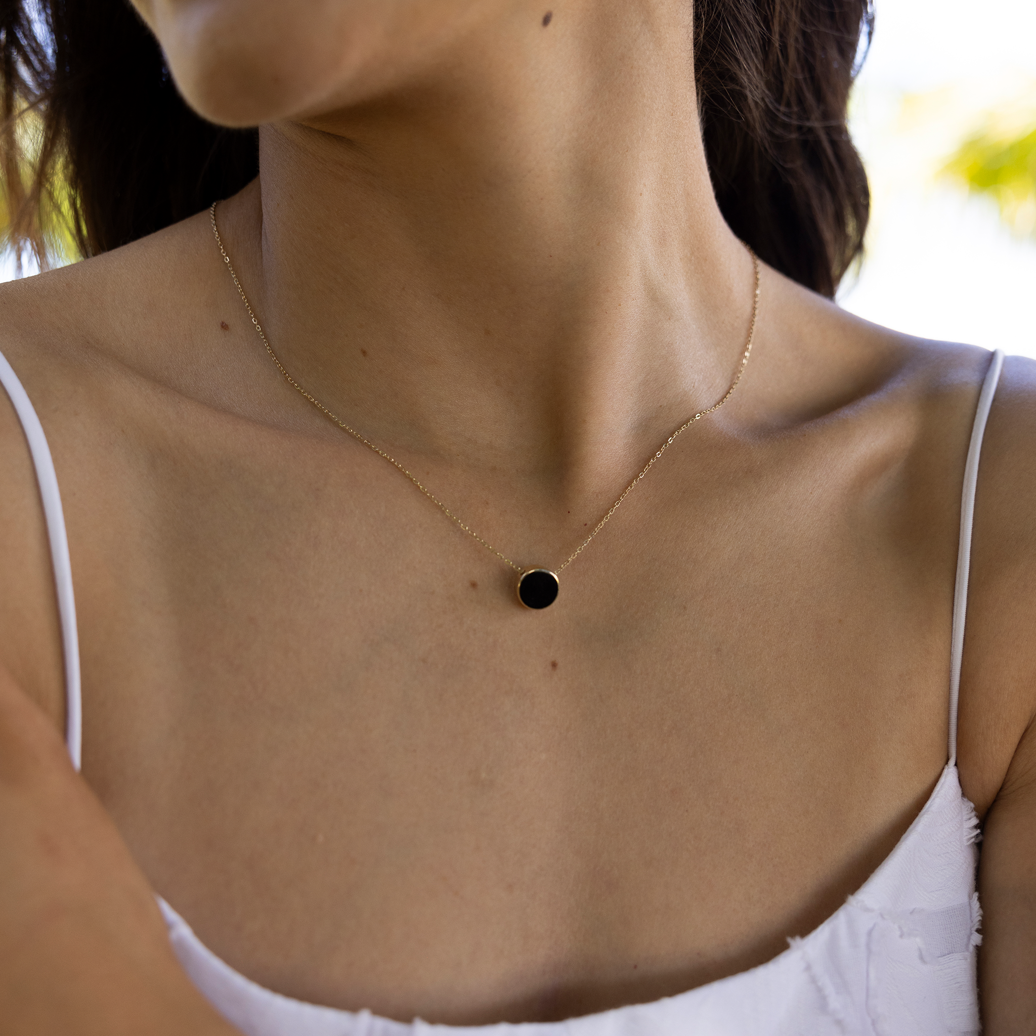 Close up of Eclipse Flipside Black Coral & Mother of Pearl Necklace in Gold on woman's neckline