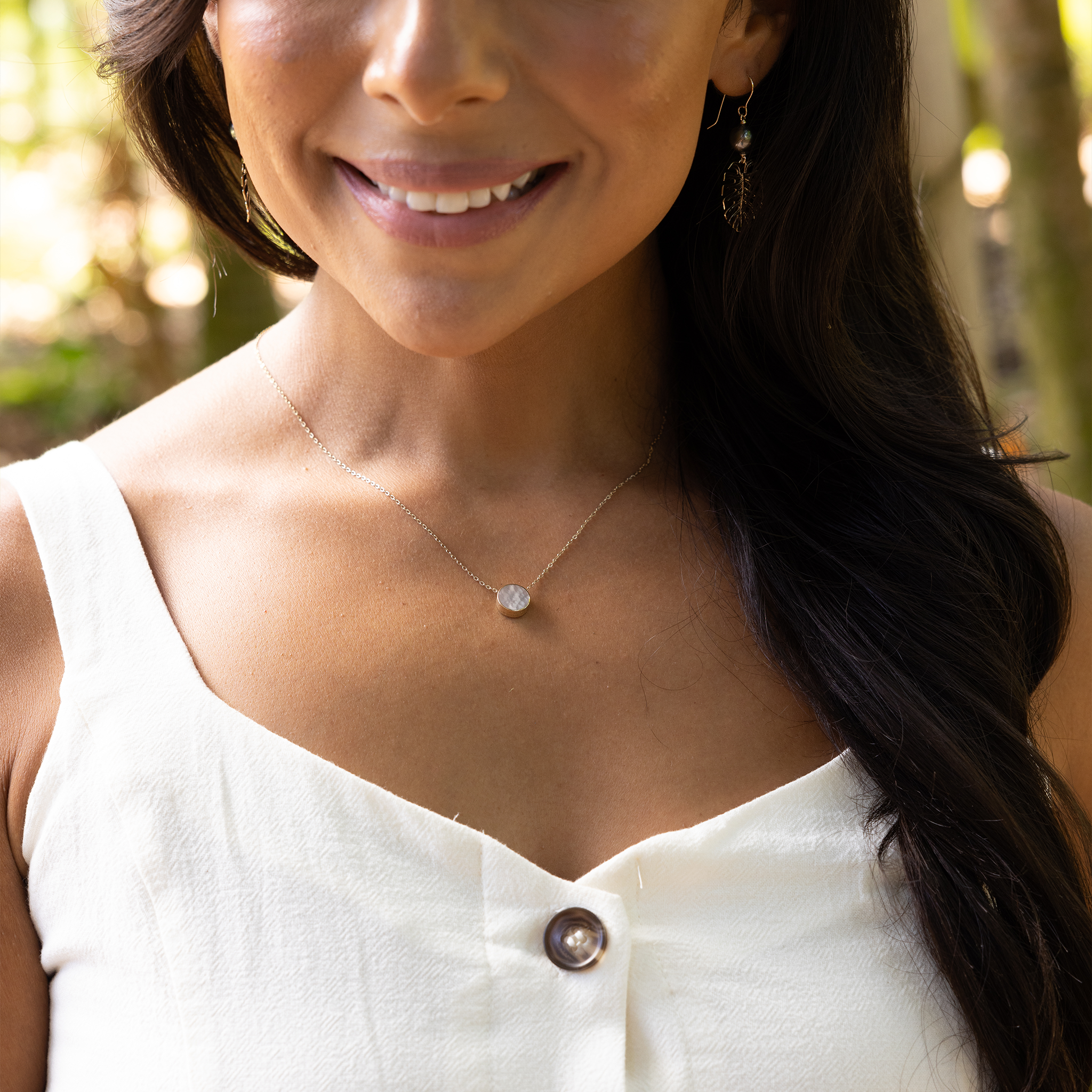 Close up of woman wearing Eclipse Flipside Black Coral & Mother of Pearl Necklace in Gold outdoors