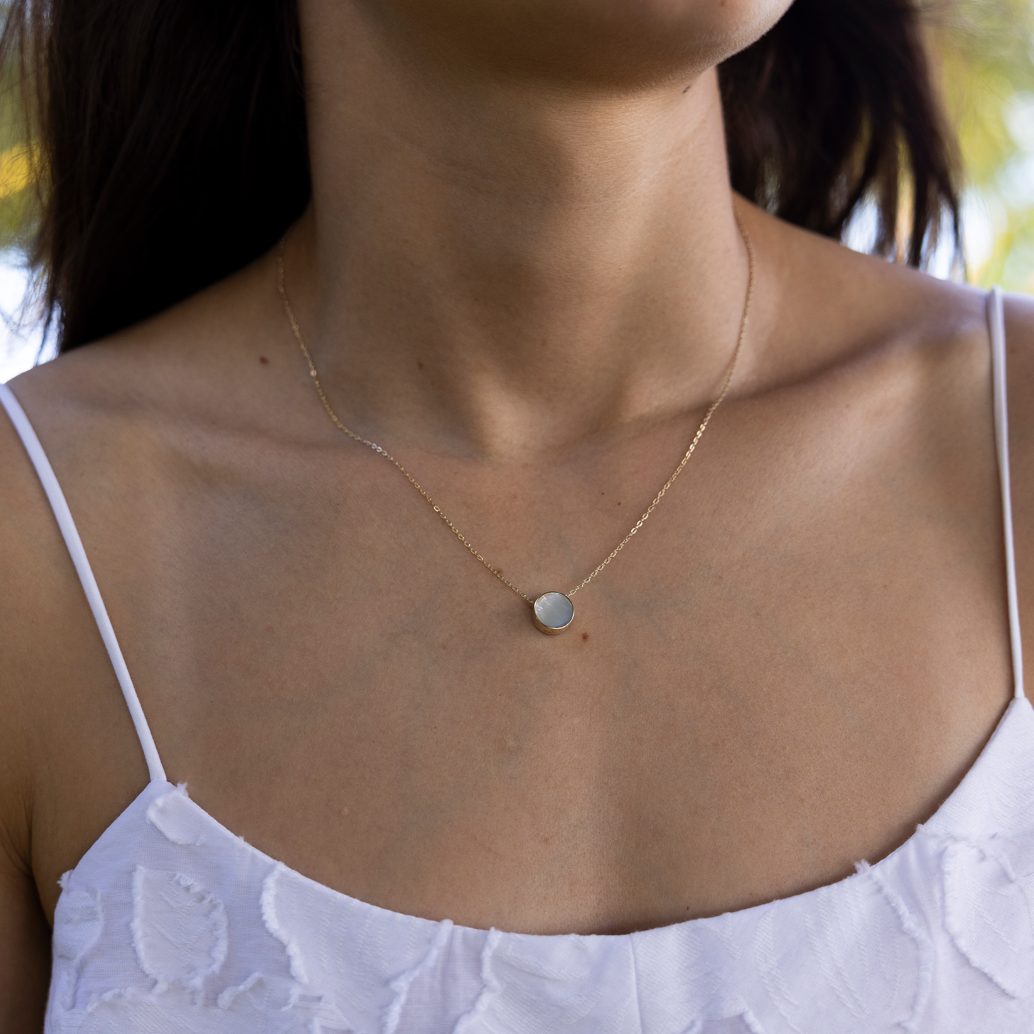 Close up of Eclipse Flipside Black Coral & Mother of Pearl Necklace in Gold on woman's neckline