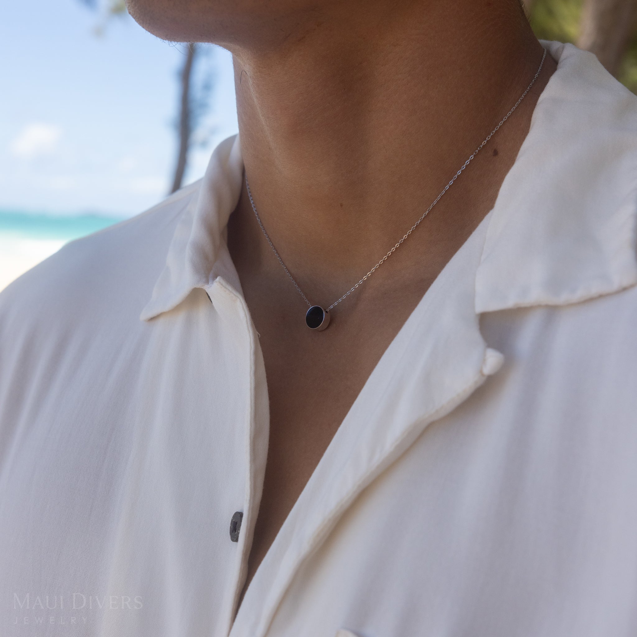 Person on beach wearing Eclipse Flipside Black Coral Necklace in White Gold