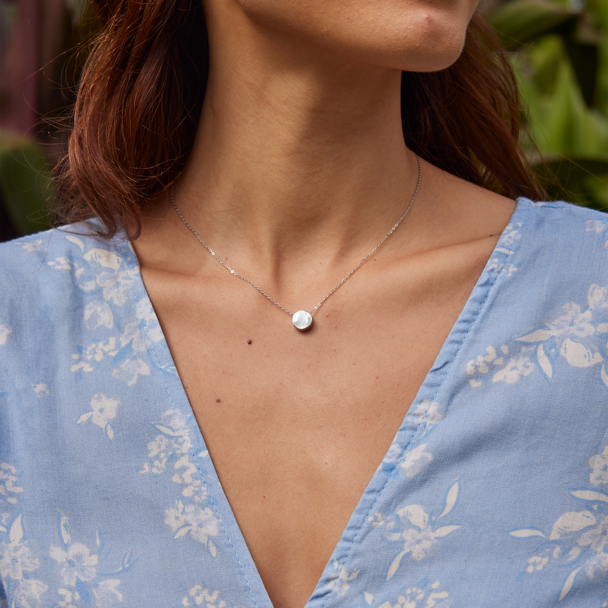 Woman in garden wearing Eclipse Flipside Mother of Pearl Necklace in White Gold
