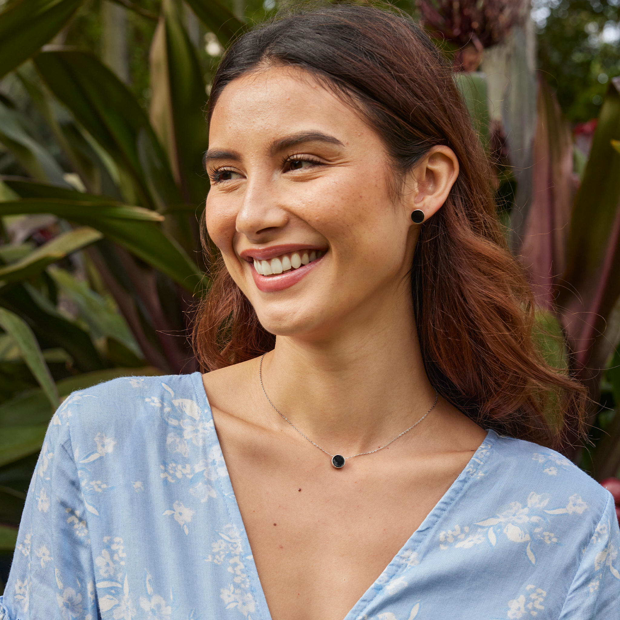 Woman in a tropical garden wearing a Eclipse Flipside Black Coral Necklace and earring in White Gold