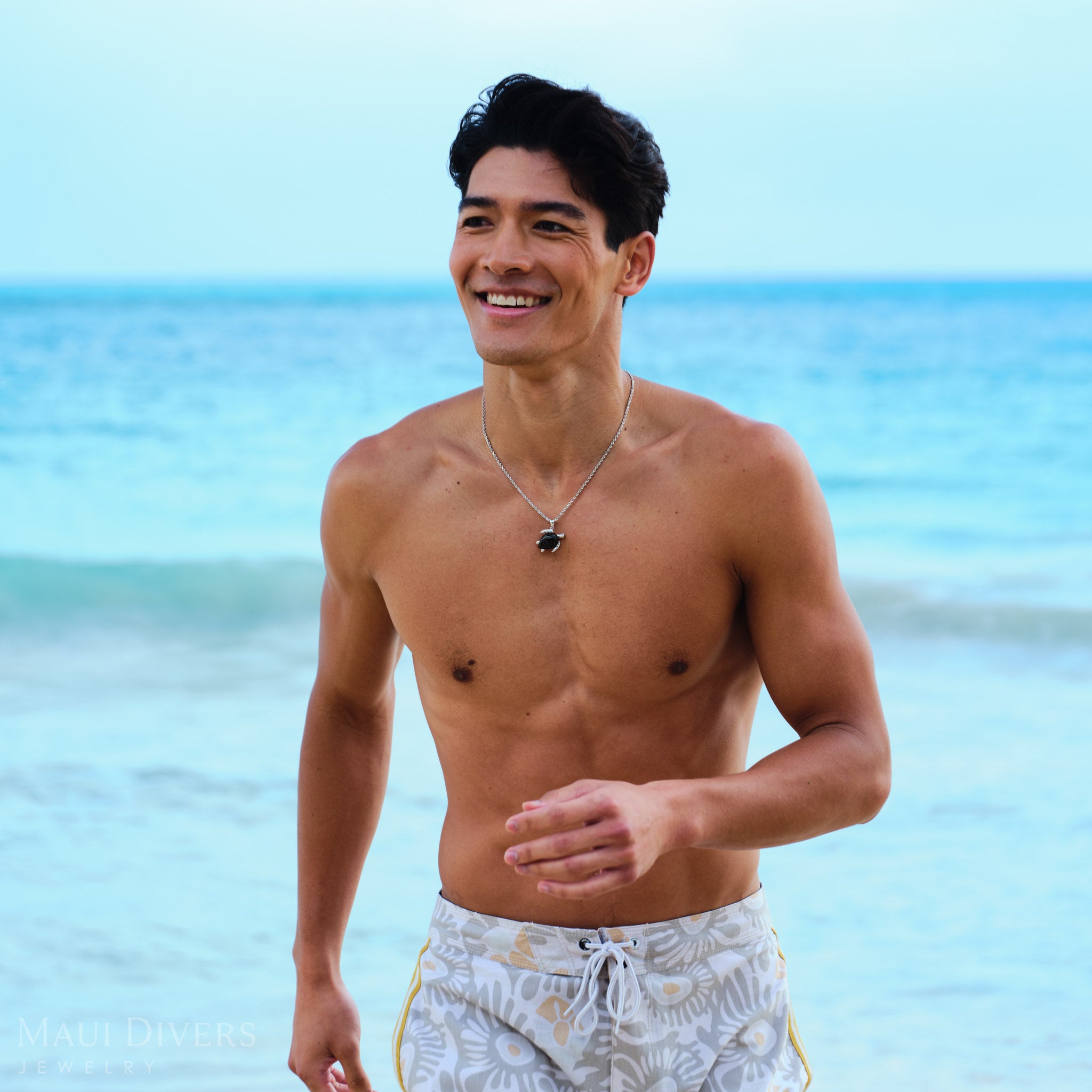 Man wearing a Honu Black Coral Pendant in White Gold with Diamonds on a beach