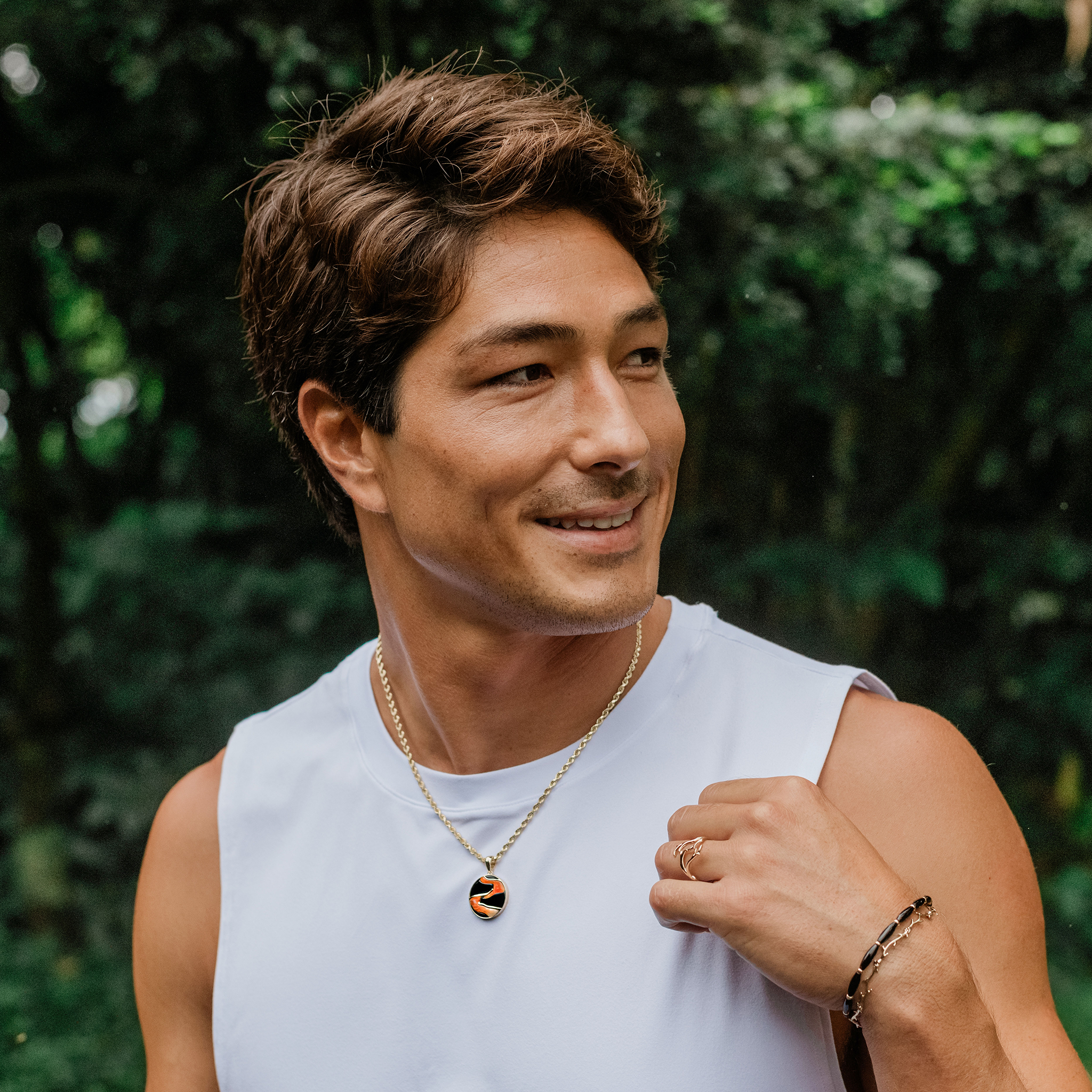 Man in forest wearing Lava Flow Black Coral and Spiny Oyster Pendant
