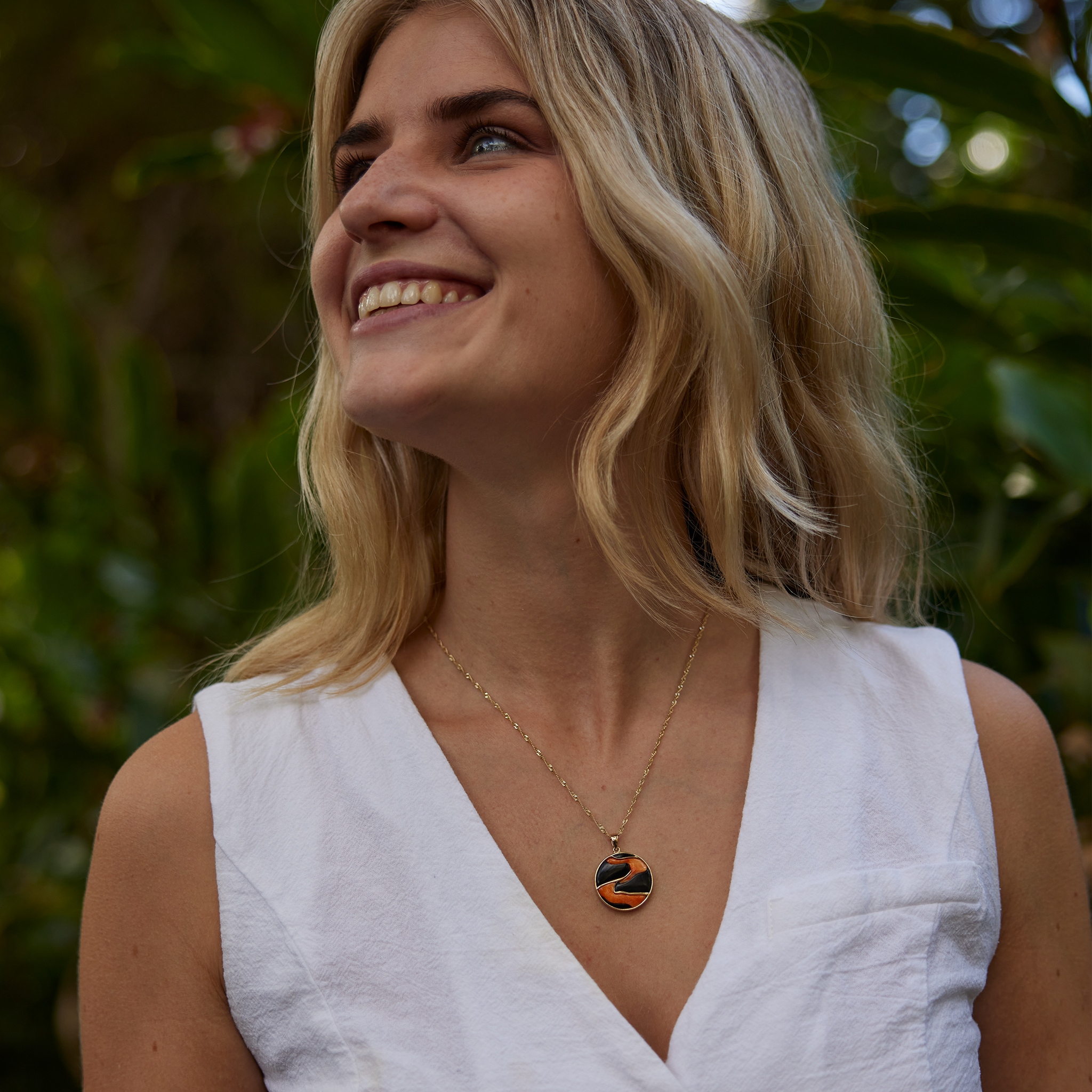 Woman in a garden wearing Lava Flow Black Coral and Spiny Oyster Pendant