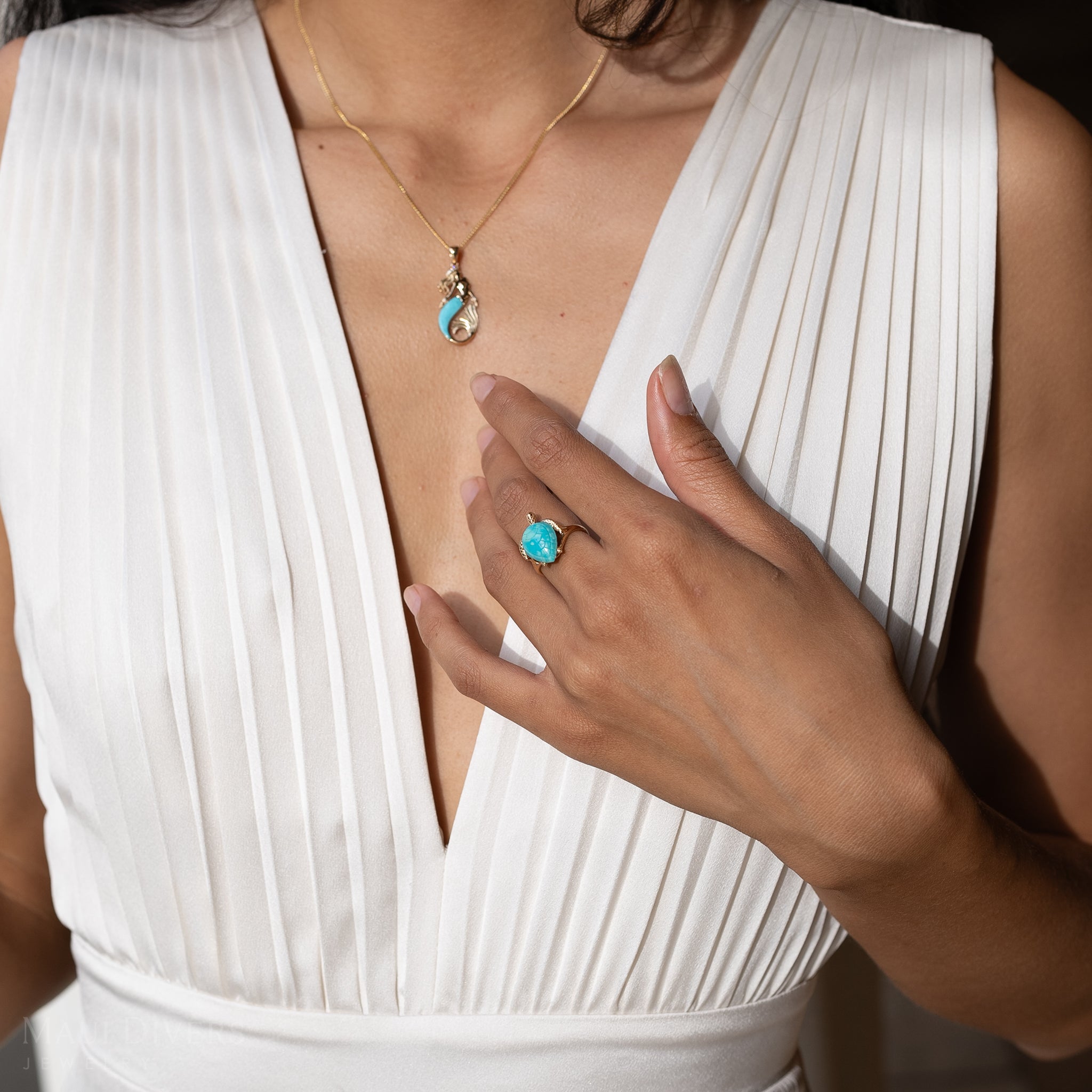 Close up of woman's chest with Honu Turquoise Ring in Gold and mermaid pendant
