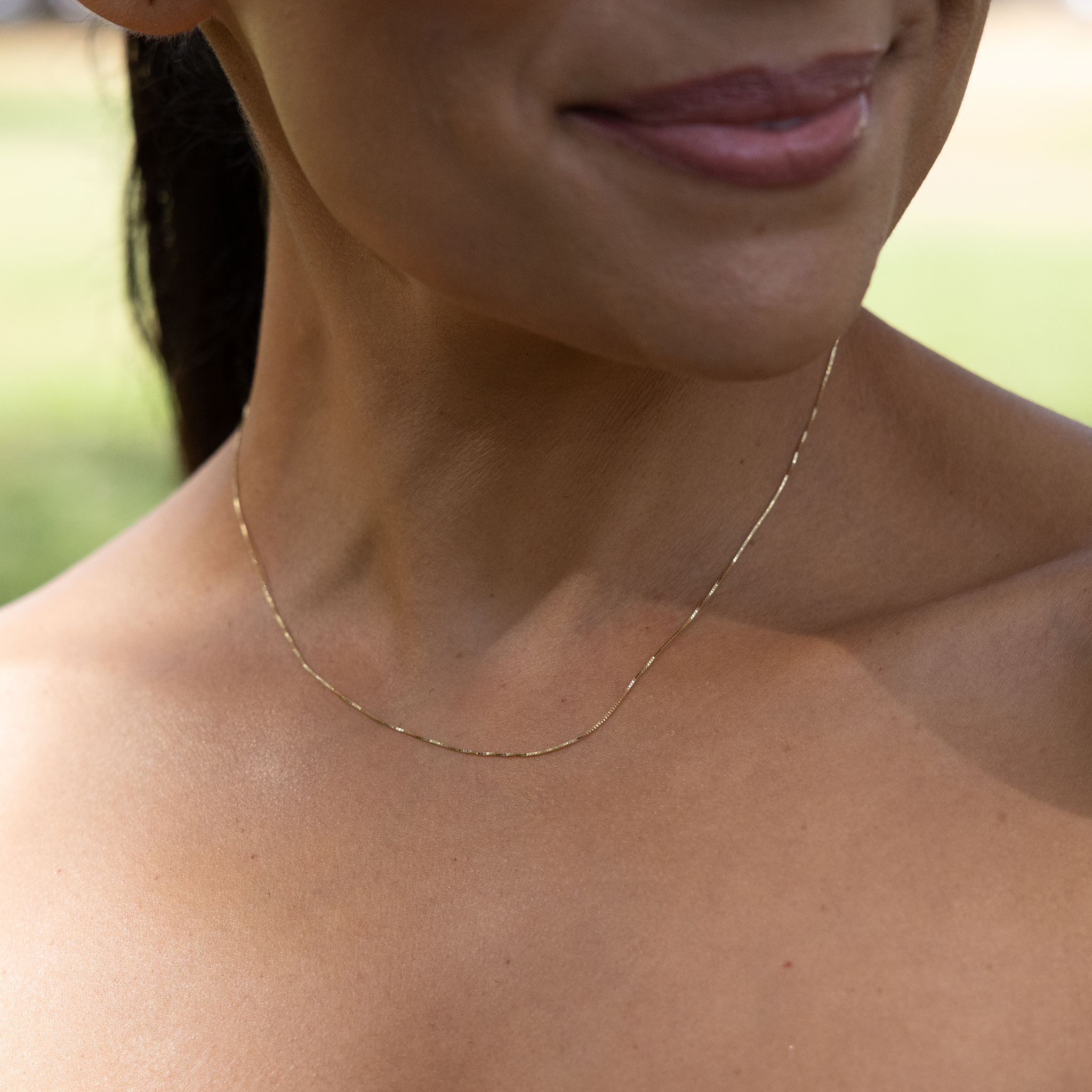 Close up of 0.6mm Box Chain in 10k Yellow Gold on woman's neckline